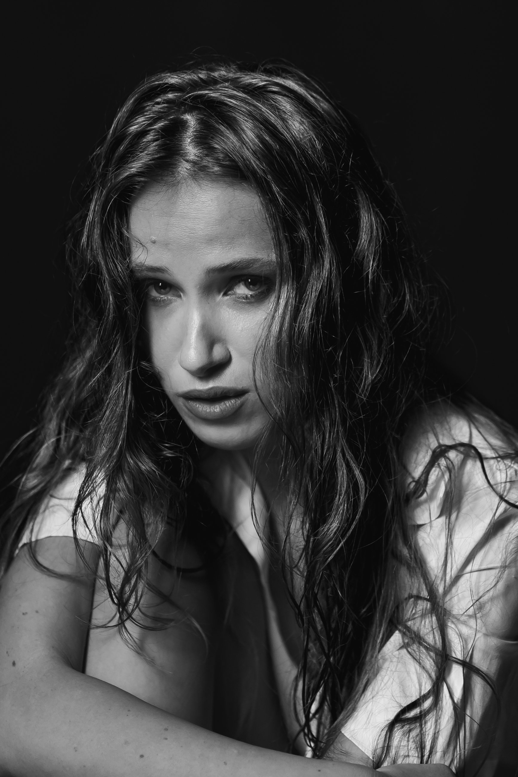 Black and white close-up portrait of a woman with wet, wavy hair, looking directly at the camera with an intense expression.