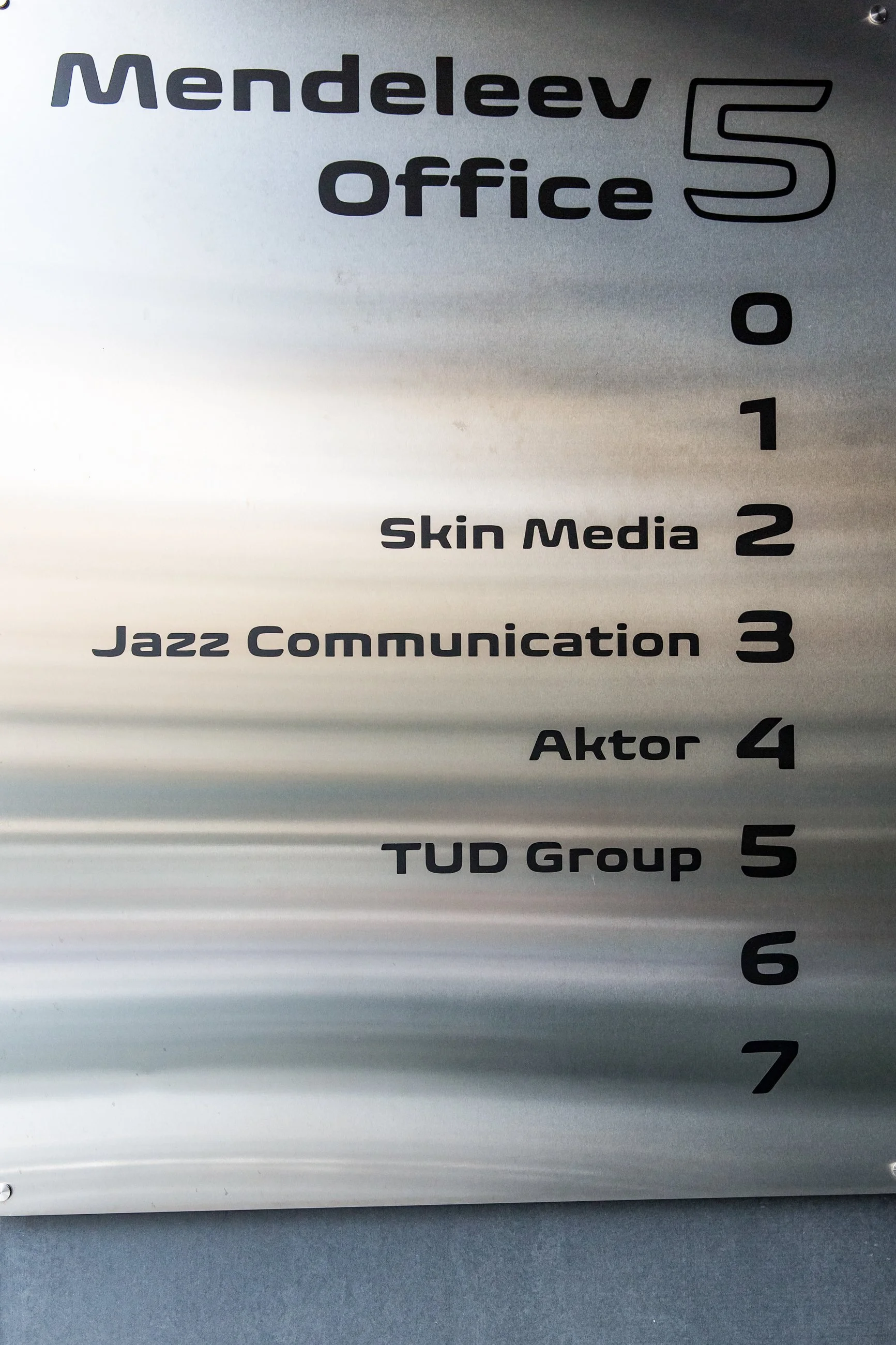 Close-up of a sign with the text 'Mendeleev office 5, Skin Media 2, Jazz Communication 3, Aktor 4, TUD Group 5' written on it.