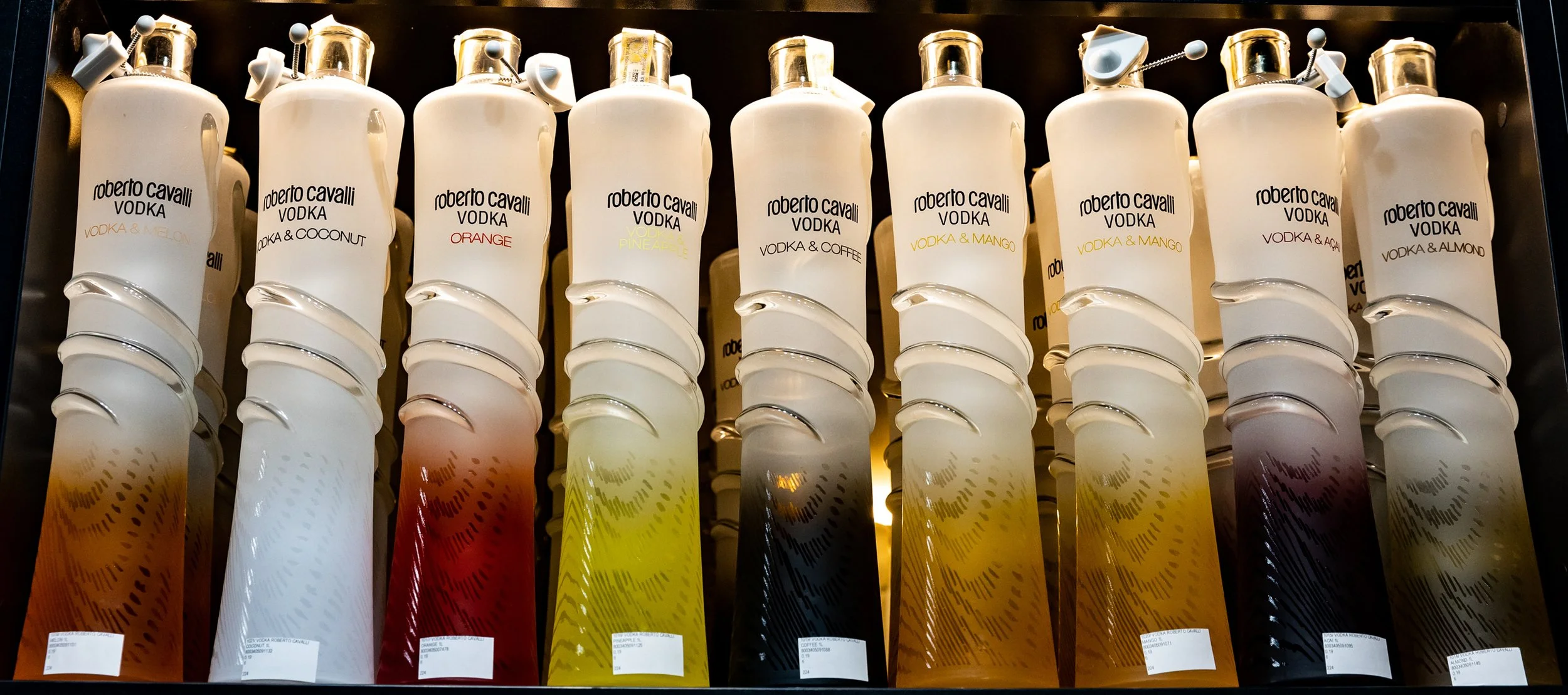 Collection of Roberto Cavalli vodka bottles with various flavored labels, arranged in a row.