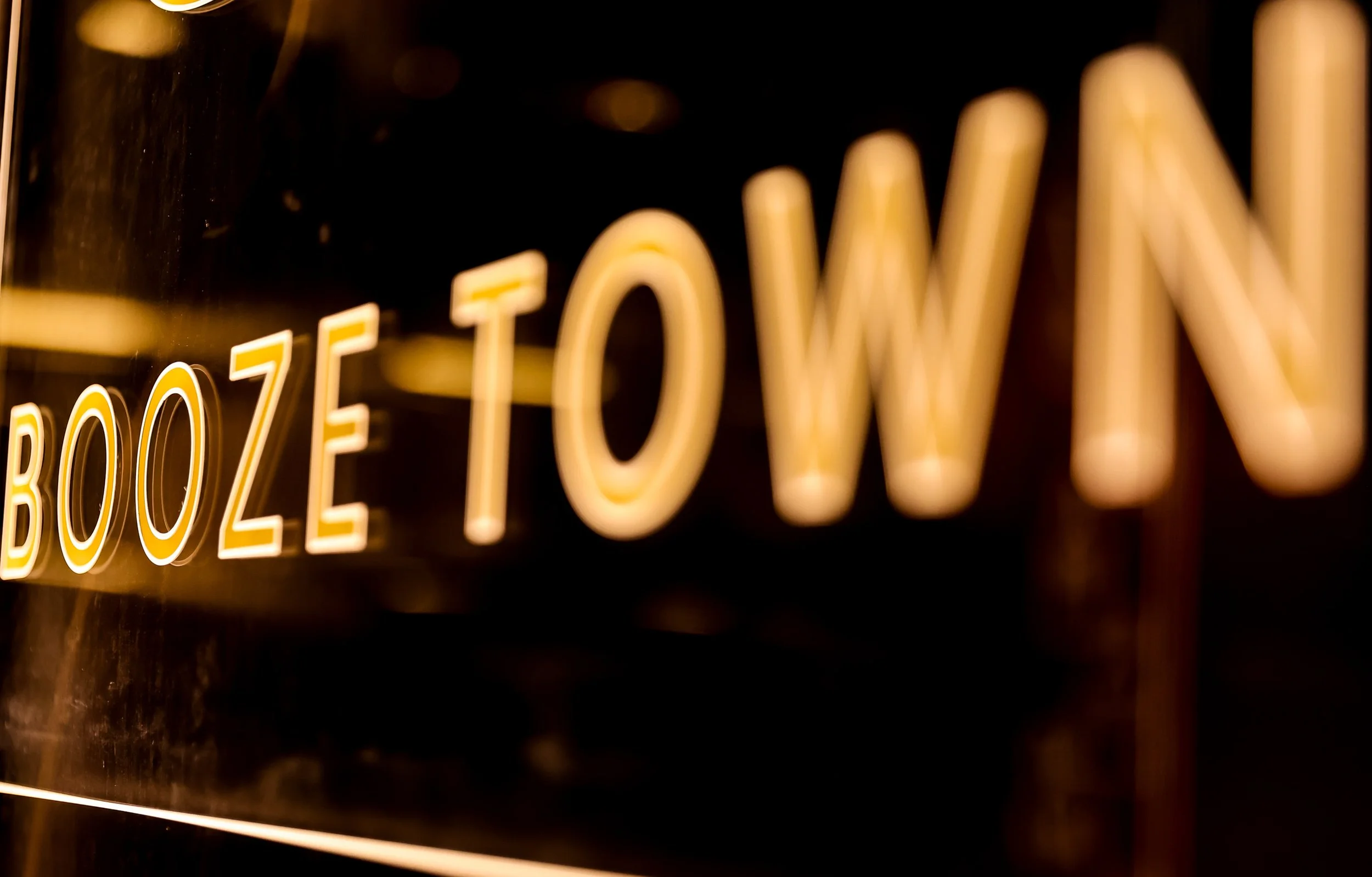 Close-up of illuminated neon sign spelling 'BOUTIQUE' in warm yellow light against a dark background.