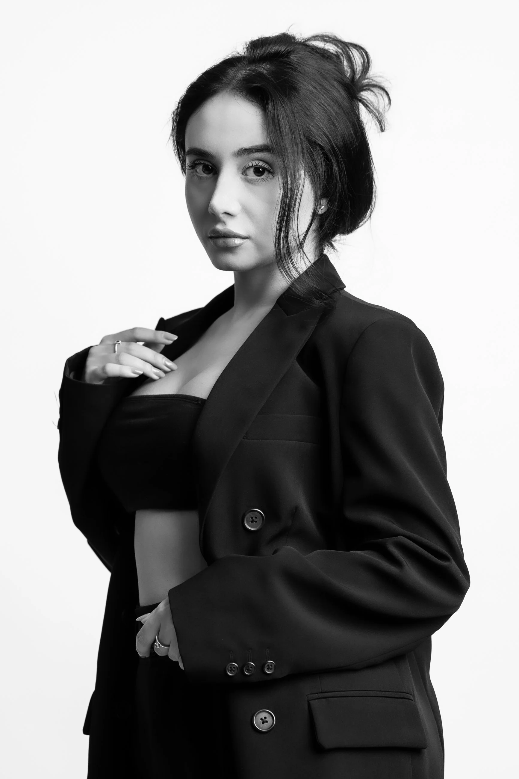 Black and white portrait of a woman with dark hair, wearing a blazer and top, looking at the camera with a serious expression.