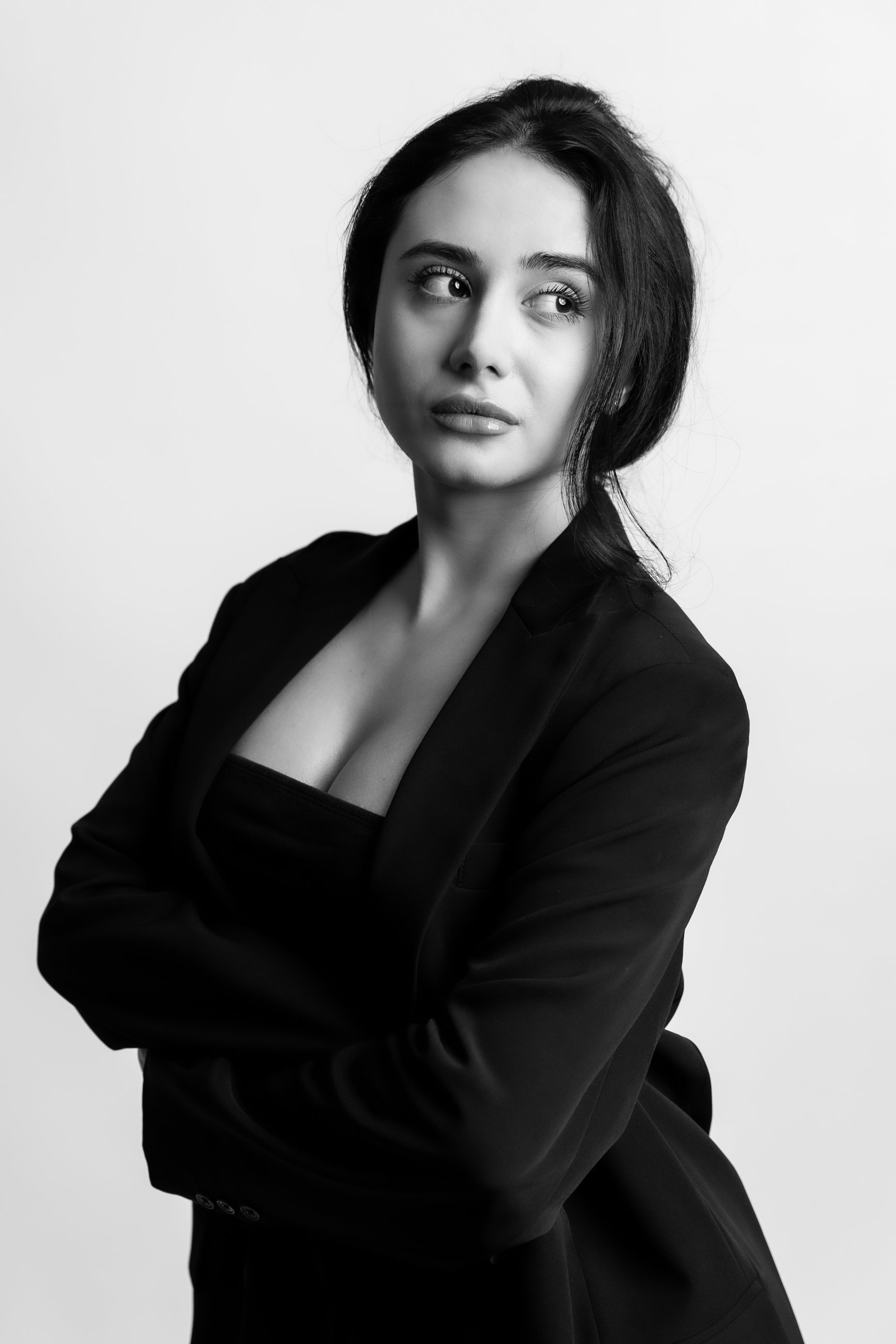 Black and white portrait of a woman with dark hair, looking to the side, wearing a blazer.