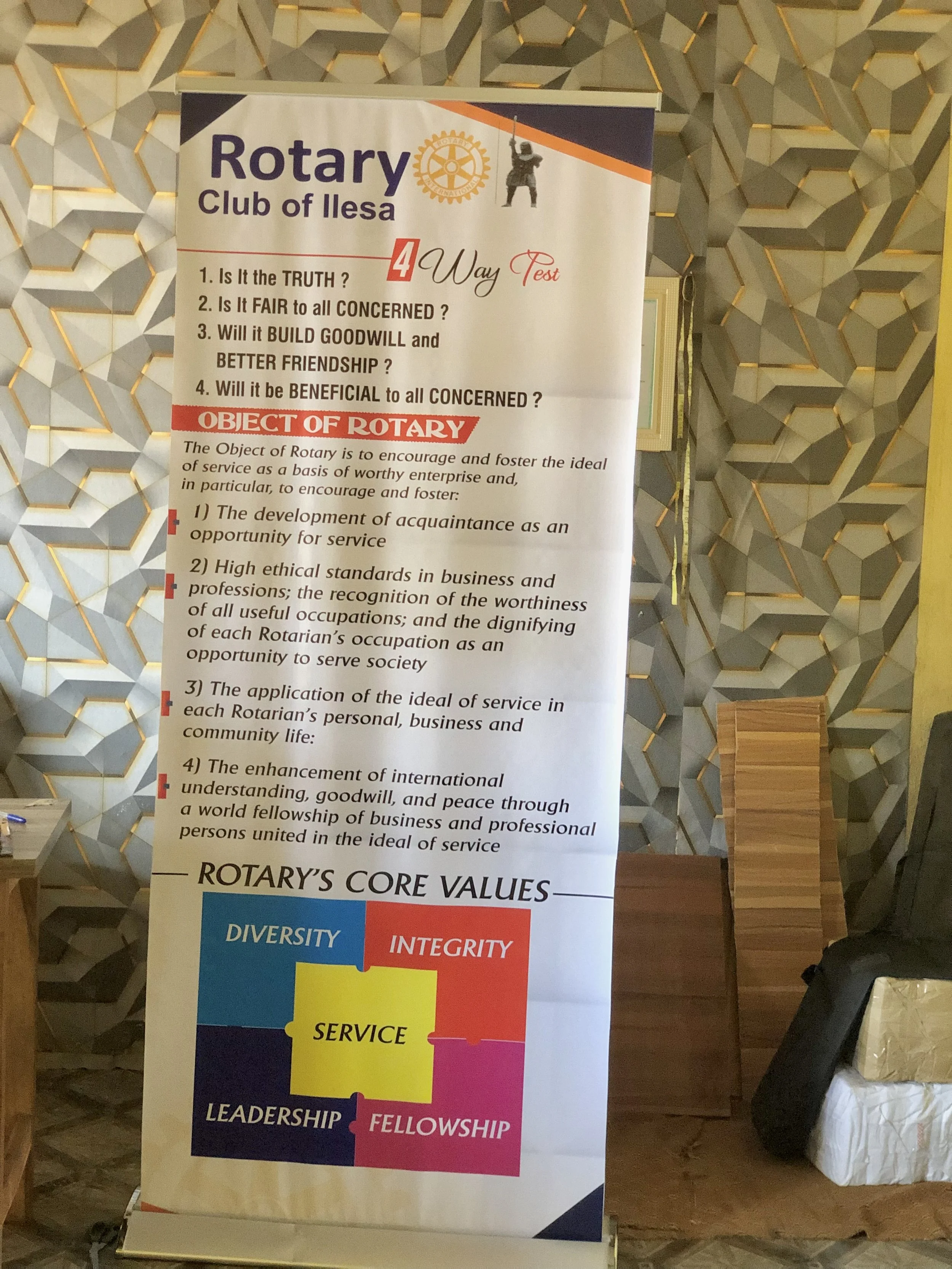 A vertical banner for the Rotary Club of Ilesa featuring a four-way test on a geometric-patterned wall. The test asks four questions about truth, fairness, goodwill, and concern, and highlights the object of Rotary for encouraging service, ethical standards, and community service. The lower part of the banner displays words representing Rotary's core values: Diversity, Integrity, Leadership, Fellowship, Service.