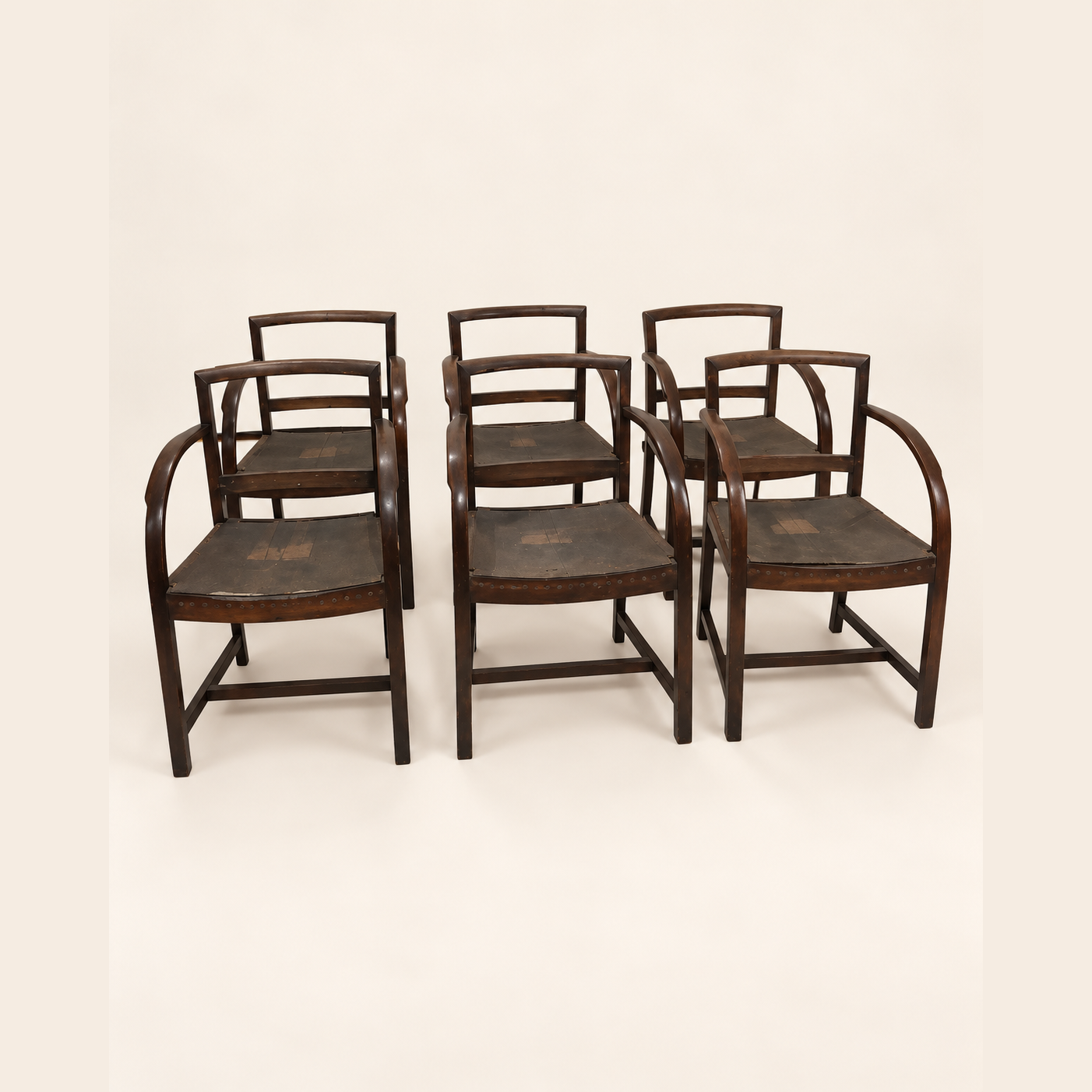 Before reupholstery: six dark wooden armchairs with bare frames and uncovered seats