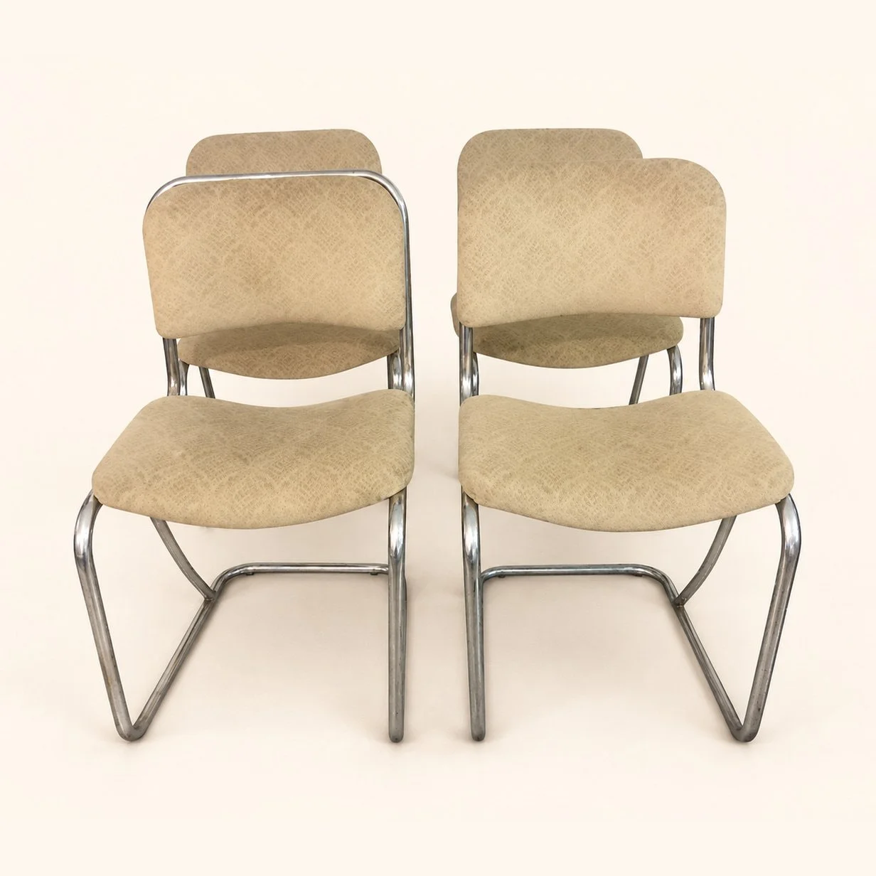 Set of chrome-frame chairs with plain beige upholstery before reupholstery.