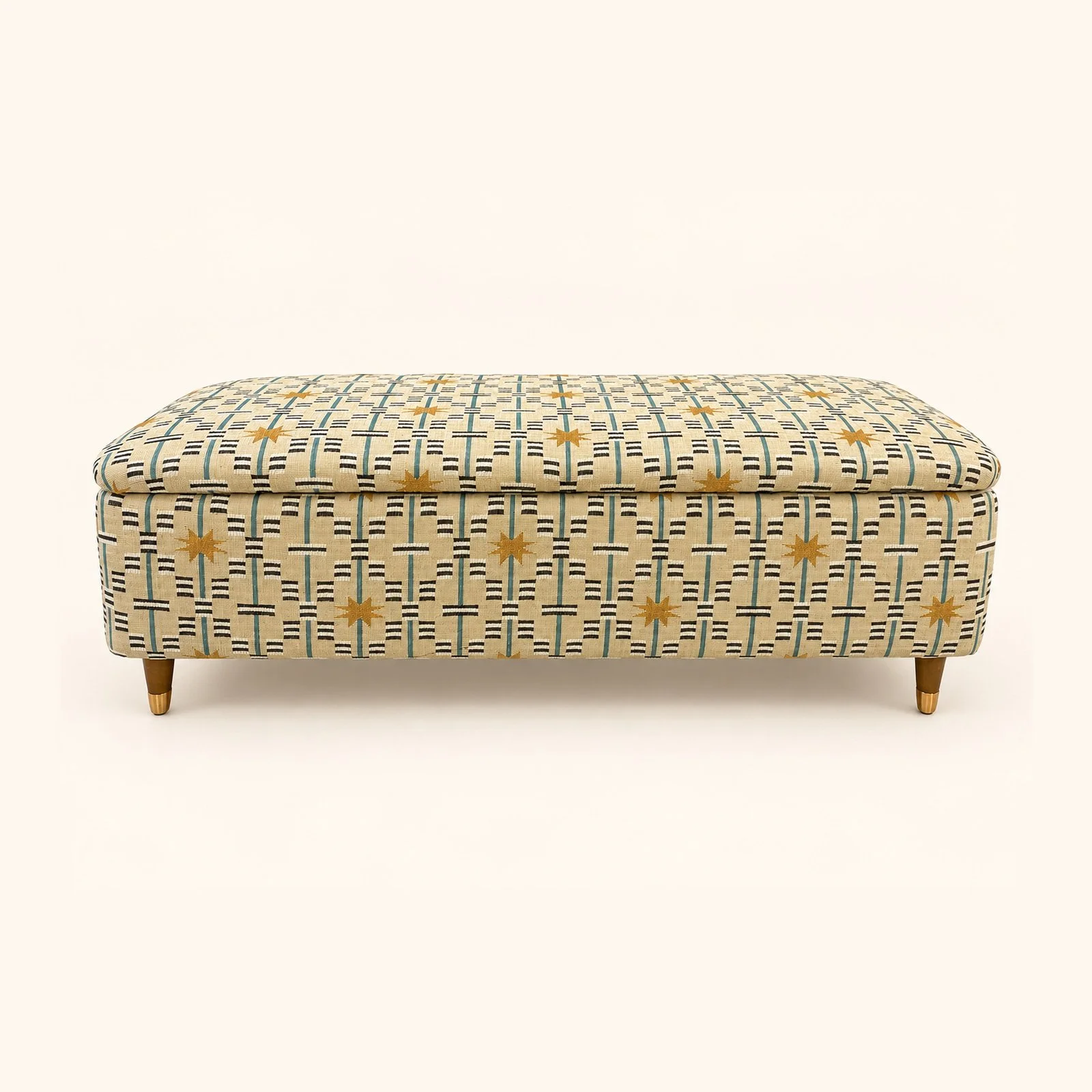 After reupholstery: a long ottoman in yellow and black geometric fabric, with a buttoned top and wooden feet.