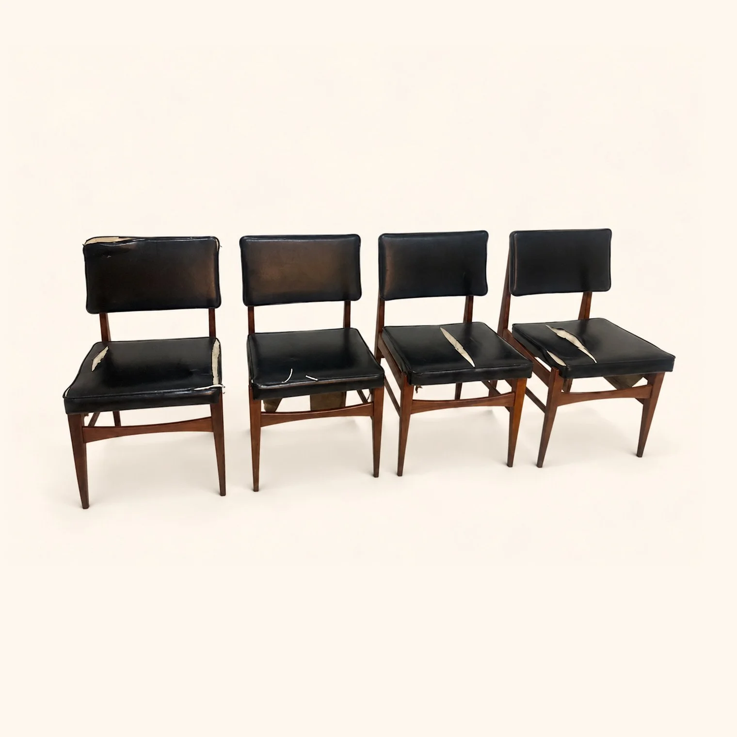 Set of wooden dining chairs with dark seats and backs before reupholstery.