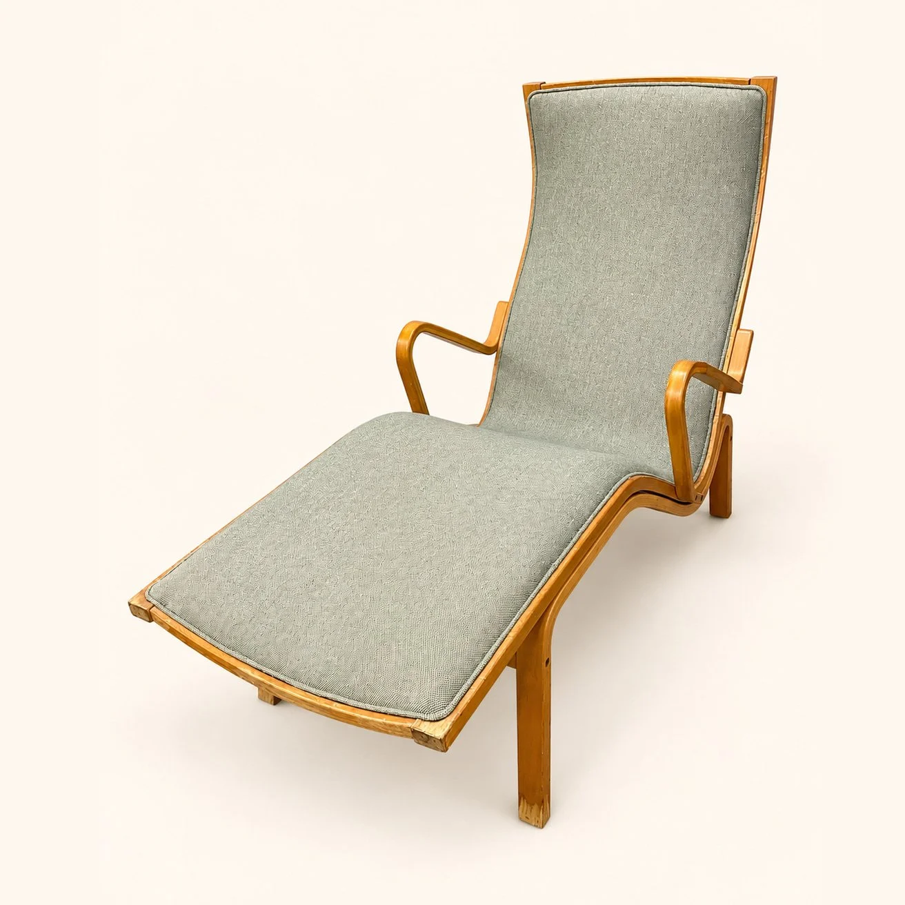 After reupholstery: a wooden lounge chair in pale blue-green fabric, with curved wooden arms and a long reclining seat.