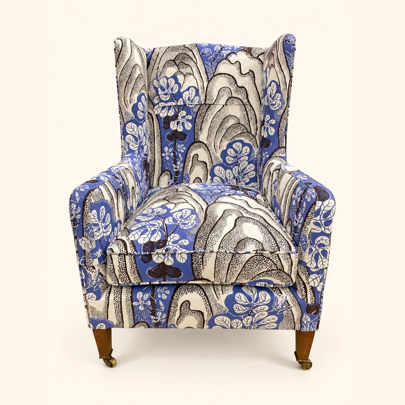 William Birch Wingback Chair after reupholstery in Josef Frank Rox and Fix fabric, with blue, cream and grey patterning, wooden legs and front castors.