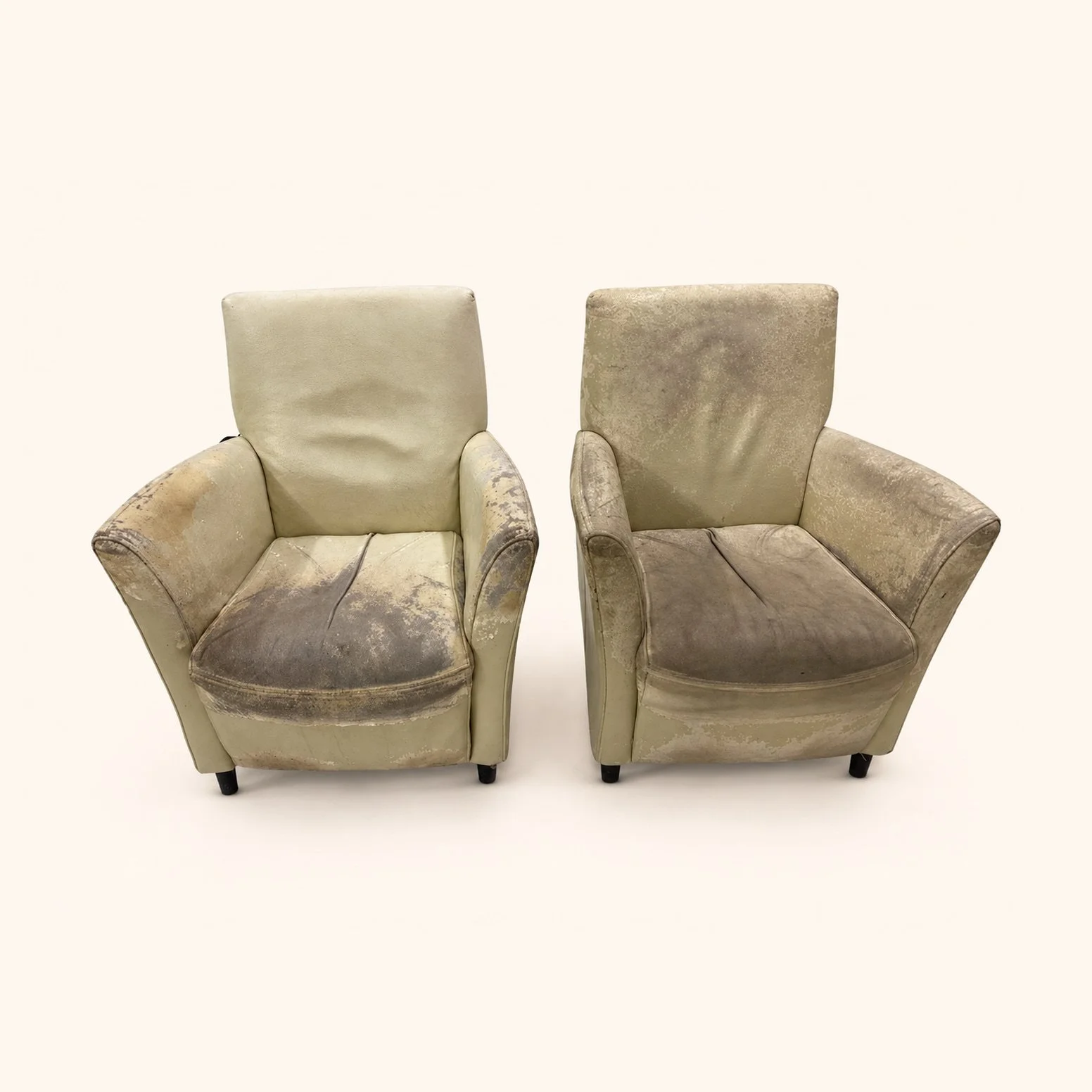 Pair of armchairs with worn neutral upholstery before reupholstery.