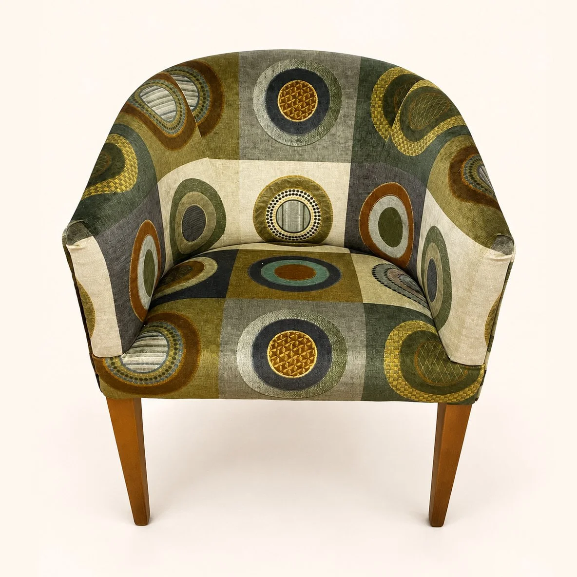 After reupholstery: a compact tub chair in a green, brown and ochre circular-patterned fabric, with a rounded back and tapered wooden legs.
