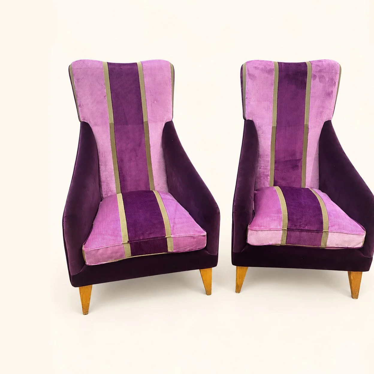 After reupholstery: a pair of tall high-back chairs in purple and pink fabric panels, with narrow gold-coloured stripes and tapered wooden legs.