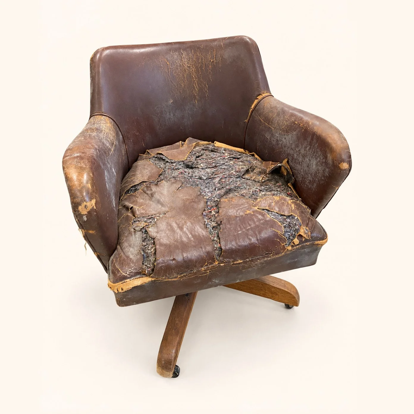 Mid-Century Swivel Chair before reupholstery, with worn brown leather and an exposed, damaged seat.