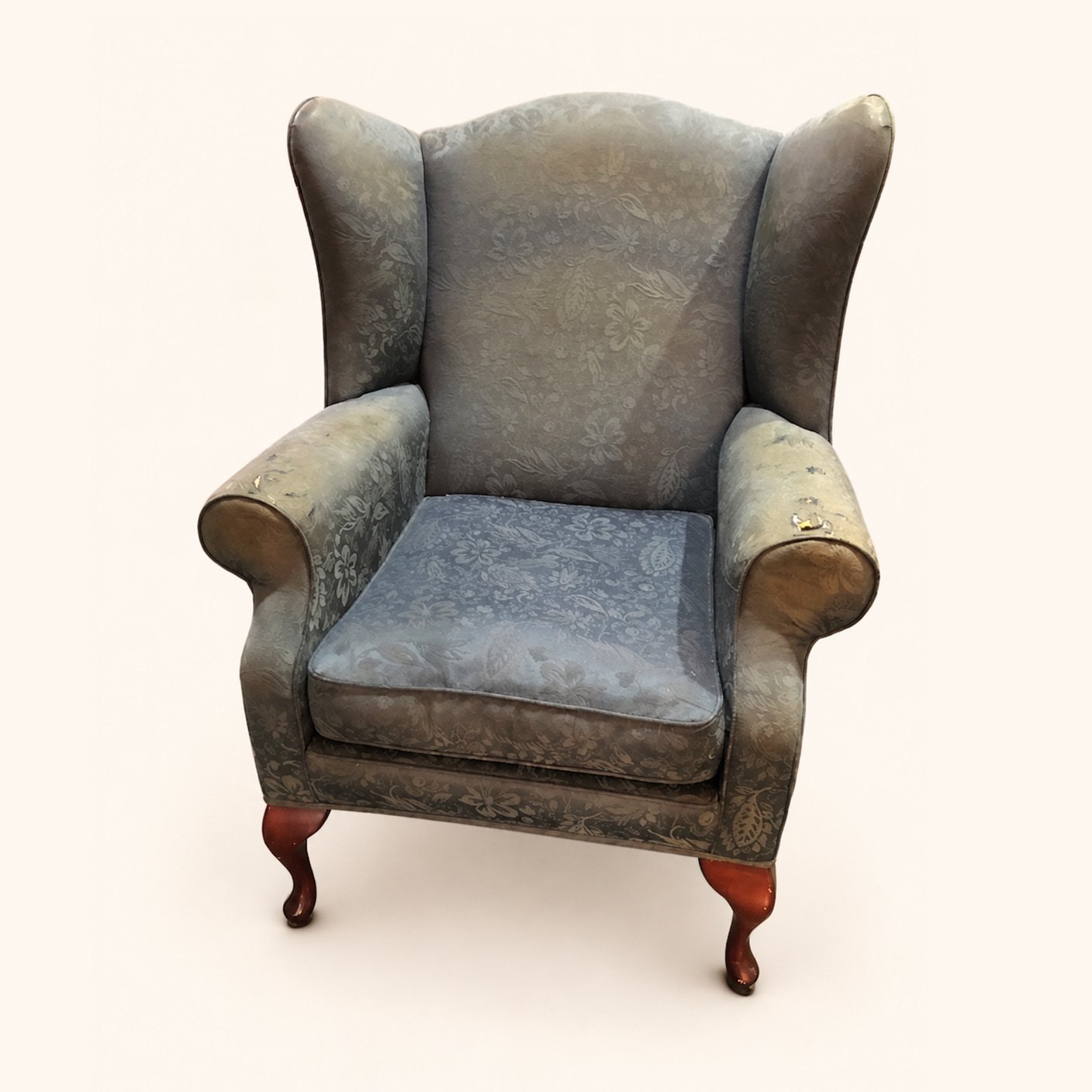 Wingback armchair in worn floral upholstery before reupholstery.