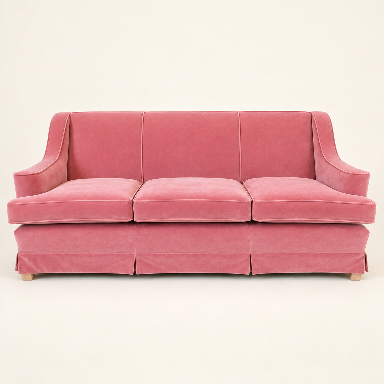 Pink three-seat sofa with piped seams, slim sloping arms, three seat cushions and a pleated skirt