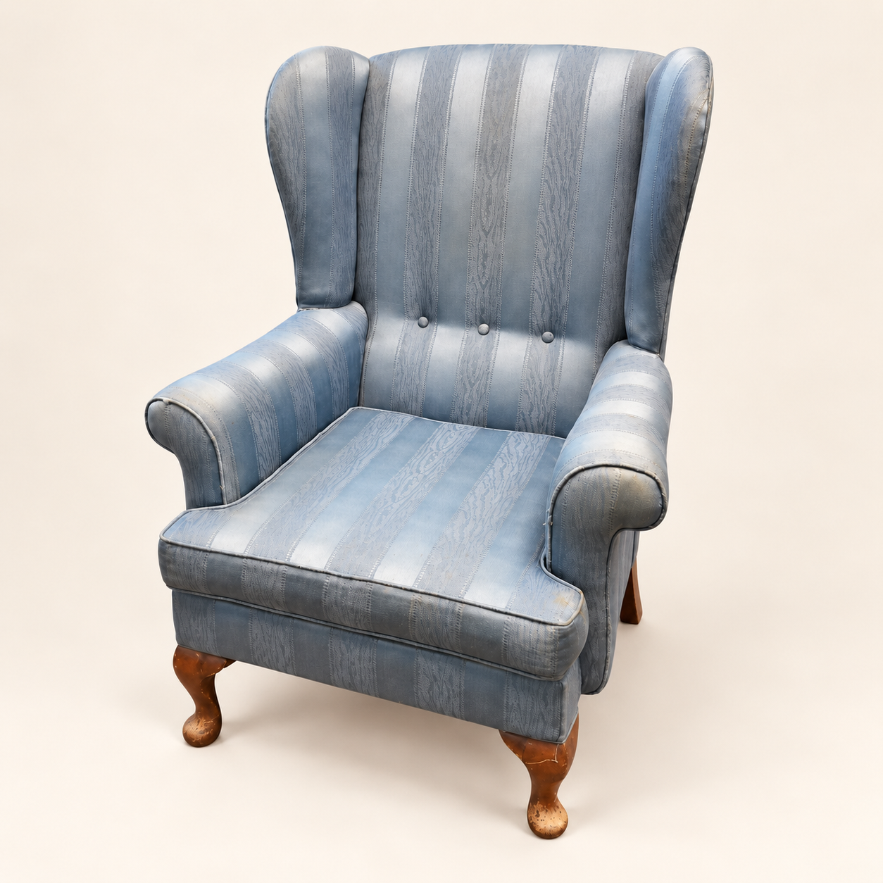 Parker Knoll Armchair before reupholstery, in pale blue striped fabric, with rolled arms and wooden legs.