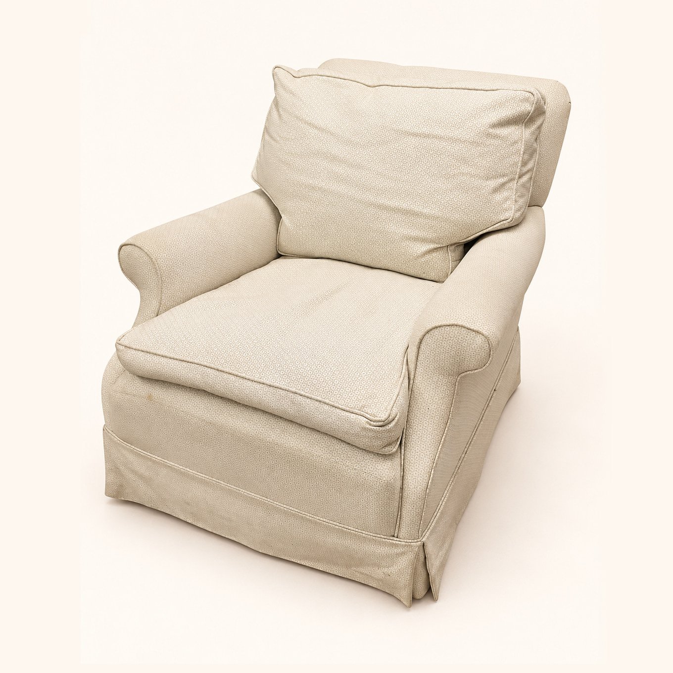 Before reupholstery: cream upholstered armchair with rounded arms, loose cushions and a fabric skirt.