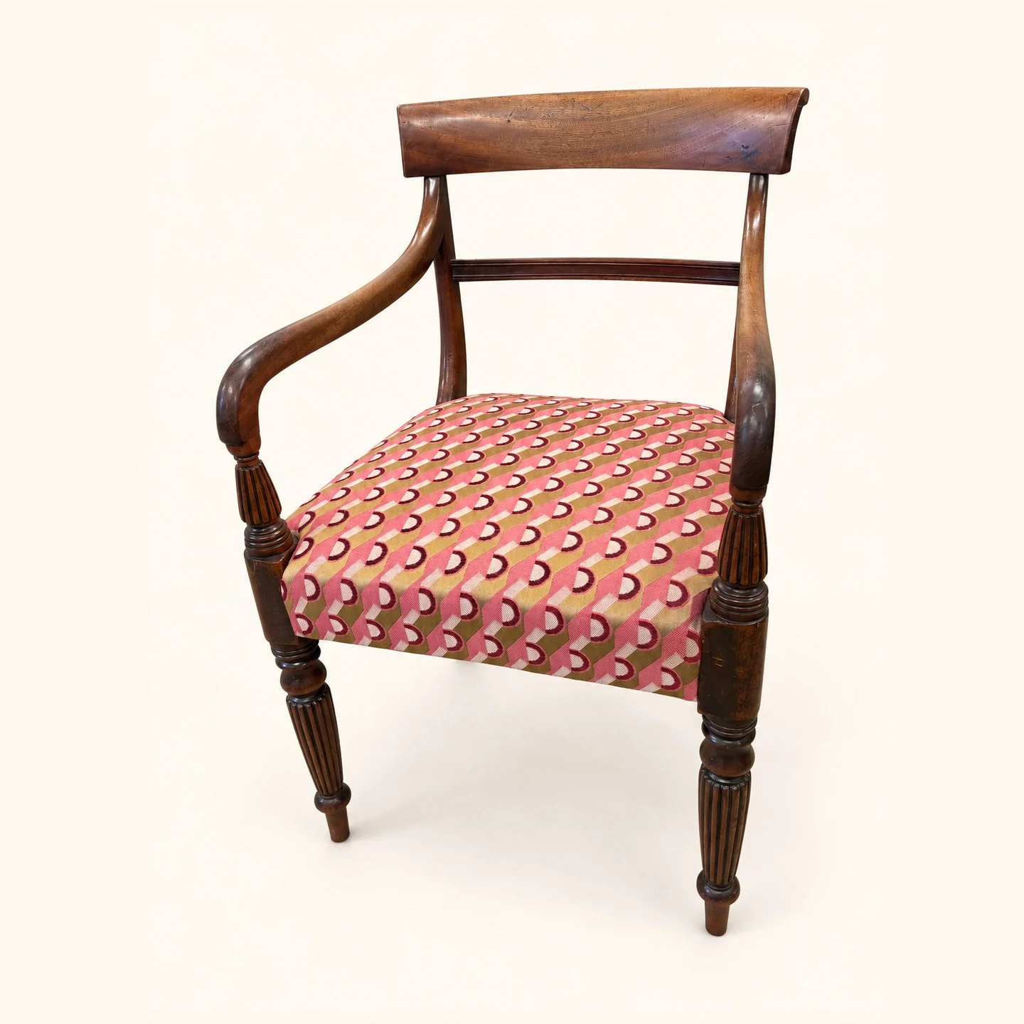 After reupholstery: a wooden dining armchair with a red patterned upholstered seat, curved arms and turned front legs.