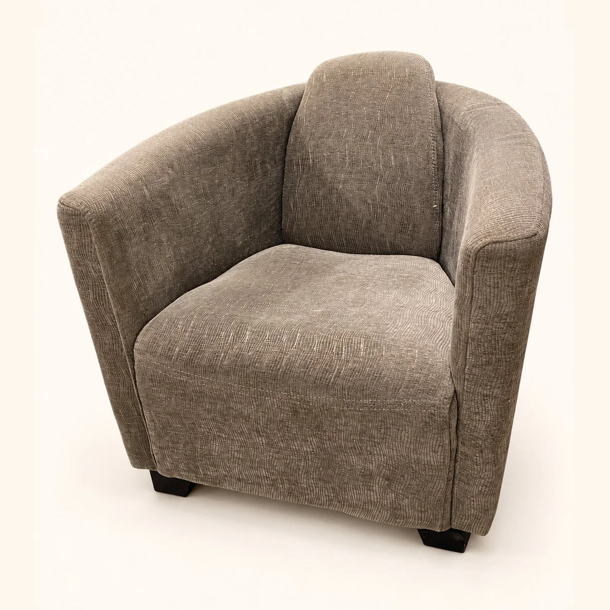 Before reupholstery: a compact tub chair in plain grey fabric, with a rounded back and low dark feet.