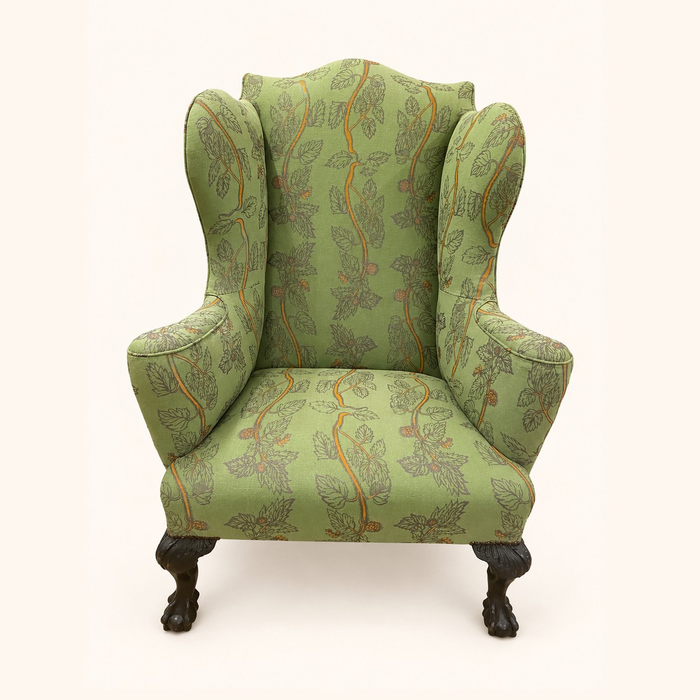 After reupholstery: a tall wingback chair in green patterned fabric, with curved arms and dark carved wooden legs.