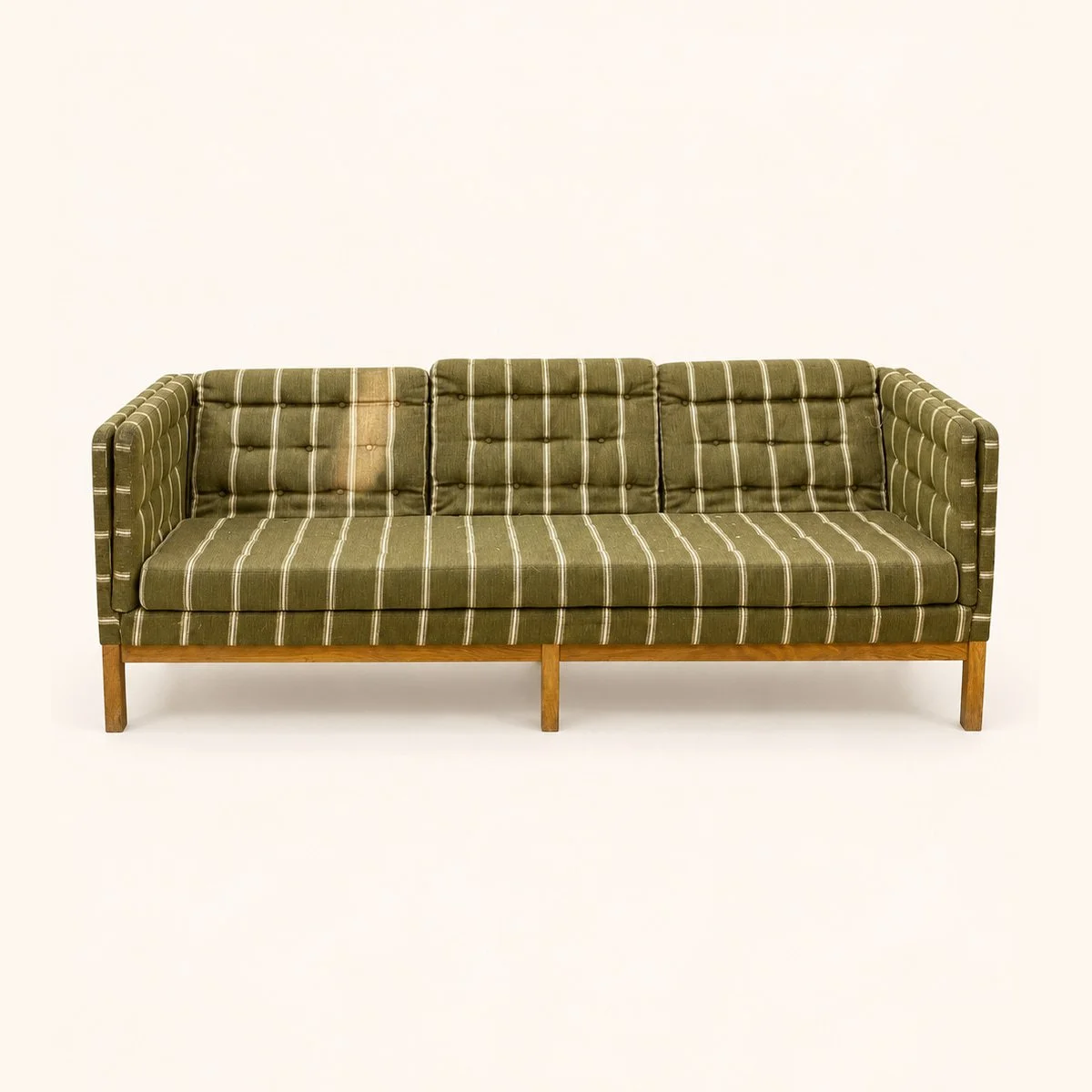 Before reupholstery: a wooden-frame sofa in green striped fabric, with a buttoned back and sides.