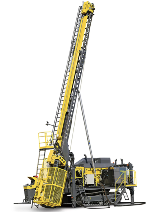 A large industrial drilling rig with a tall vertical mast, yellow safety guards, and various metal components, used for deep ground excavation or geotechnical work.