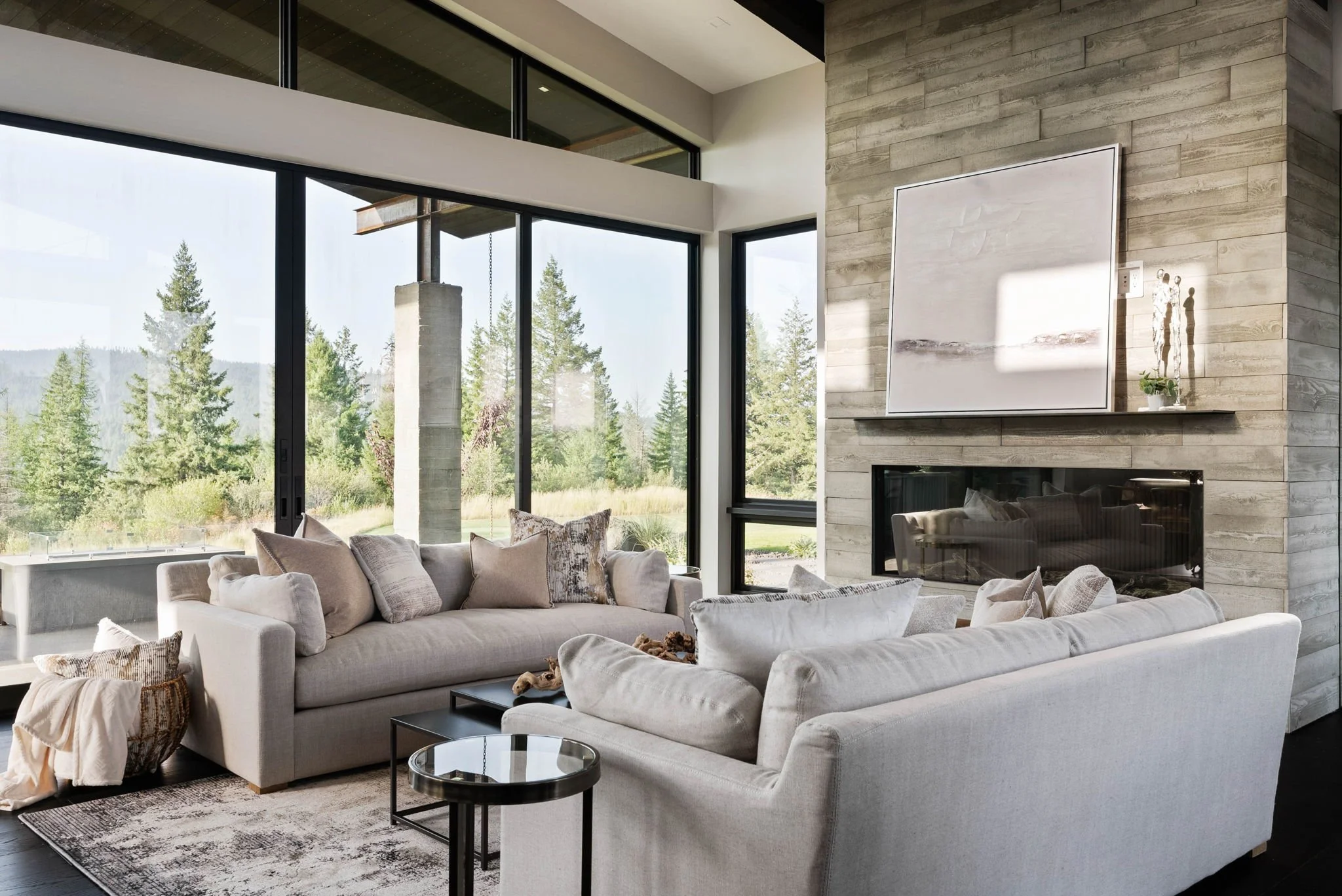 Two grey sofas facing each other in a staged living room with a modern fireplace, patterned rug and panoramic windows, capturing an inviting layout