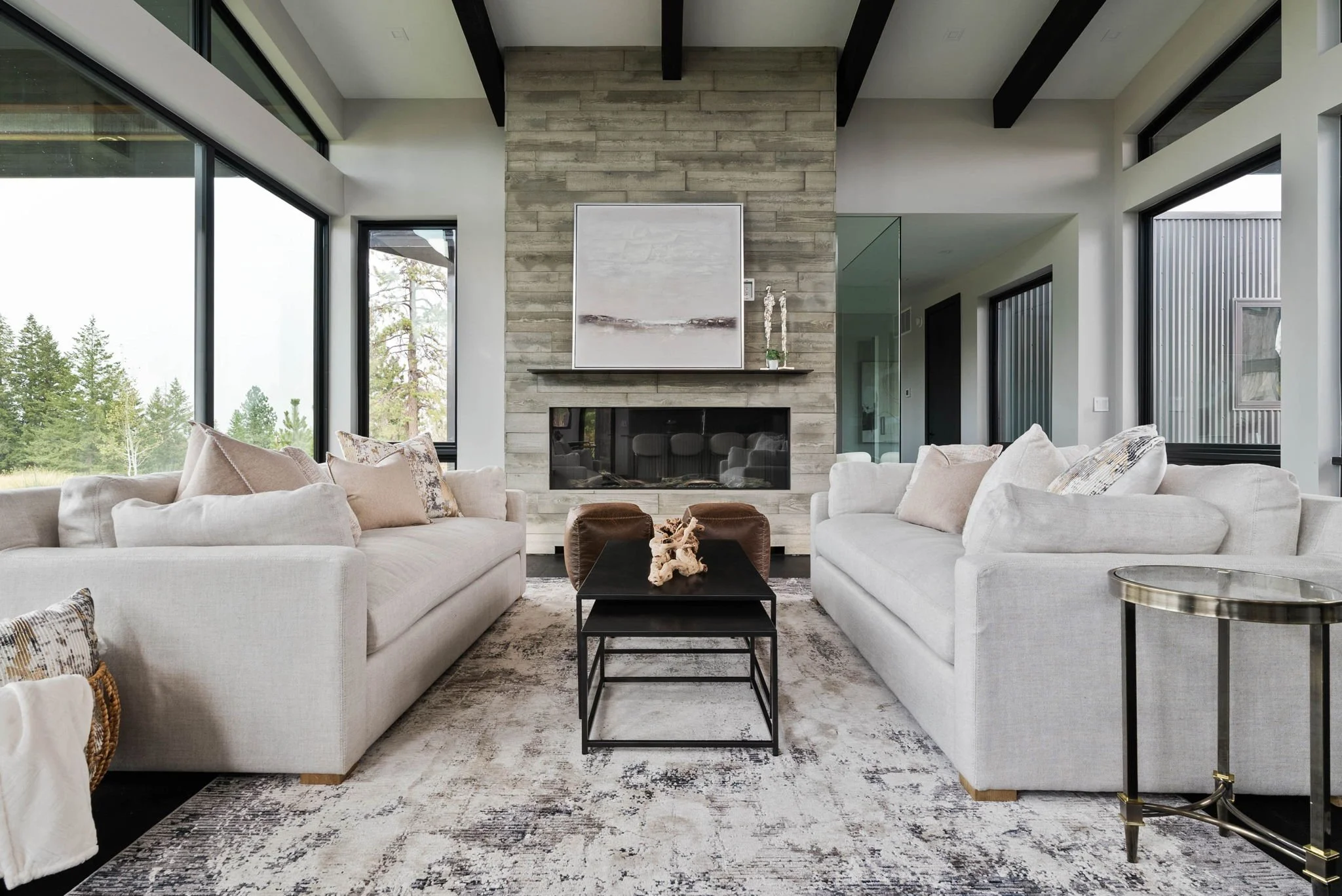 Wide‑angle view of a professionally staged living room with matching couches, a sleek fireplace and expansive windows, showcasing cohesive design and natural light