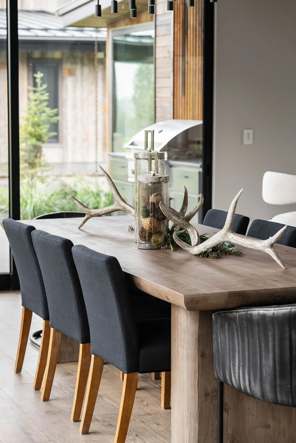 Elegant dining table set with blue chairs and a rustic antler centerpiece, blending modern and natural elements in staging