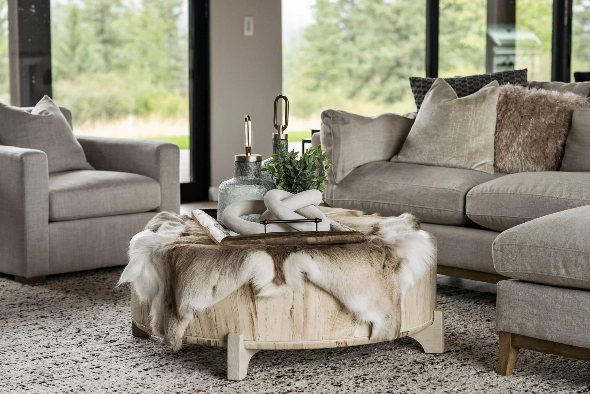 Decorative vases and natural elements arranged on a wooden table in a staged living room, reflecting the finishing touches of thoughtful design.