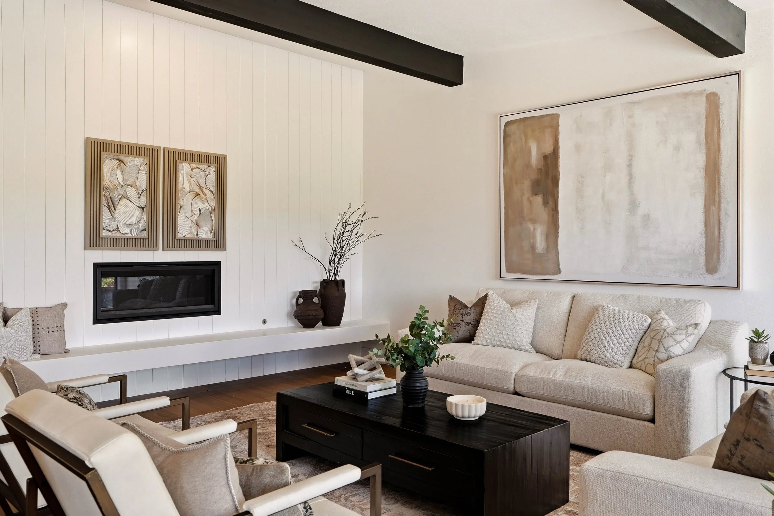 HSW-staged living room with a cream sofa, accent chairs, dark coffee table and coordinated artwork.