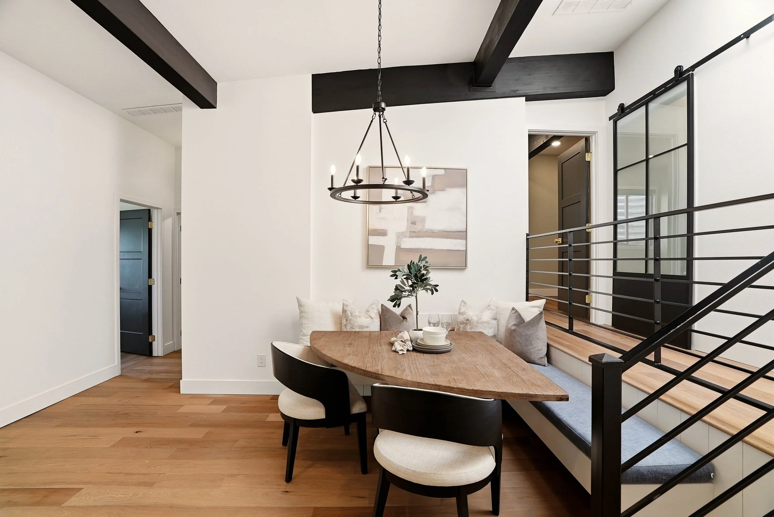 A modern dining space with a wood table, dark chairs and an open stair rail. Staging by Home Staging Works.