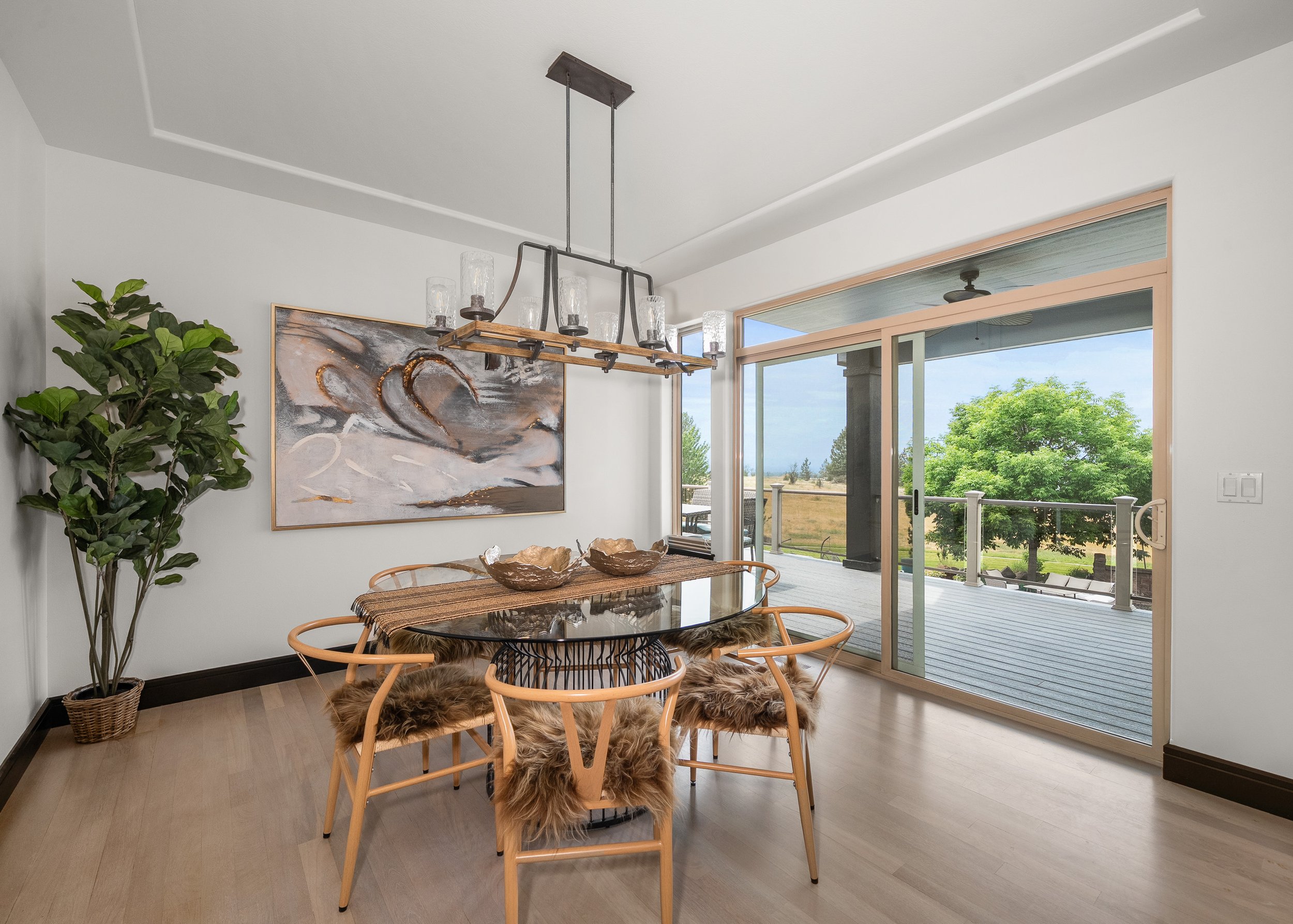 A light-filled dining space with a round wood table and soft neutral seating. Staging by Home Staging Works.