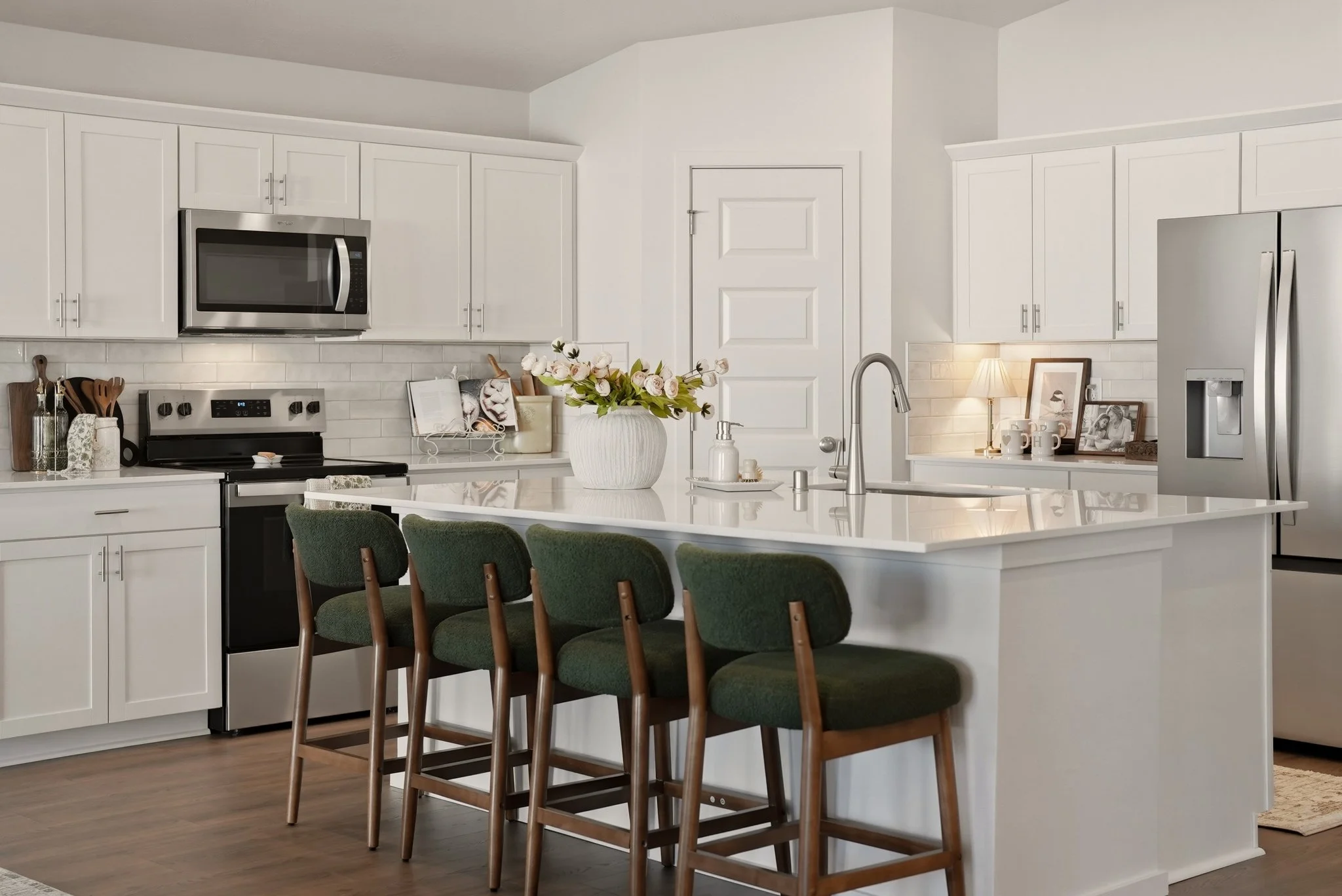 A bright kitchen styled by HSW with white cabinetry, green counter stools and coordinated details around the island.