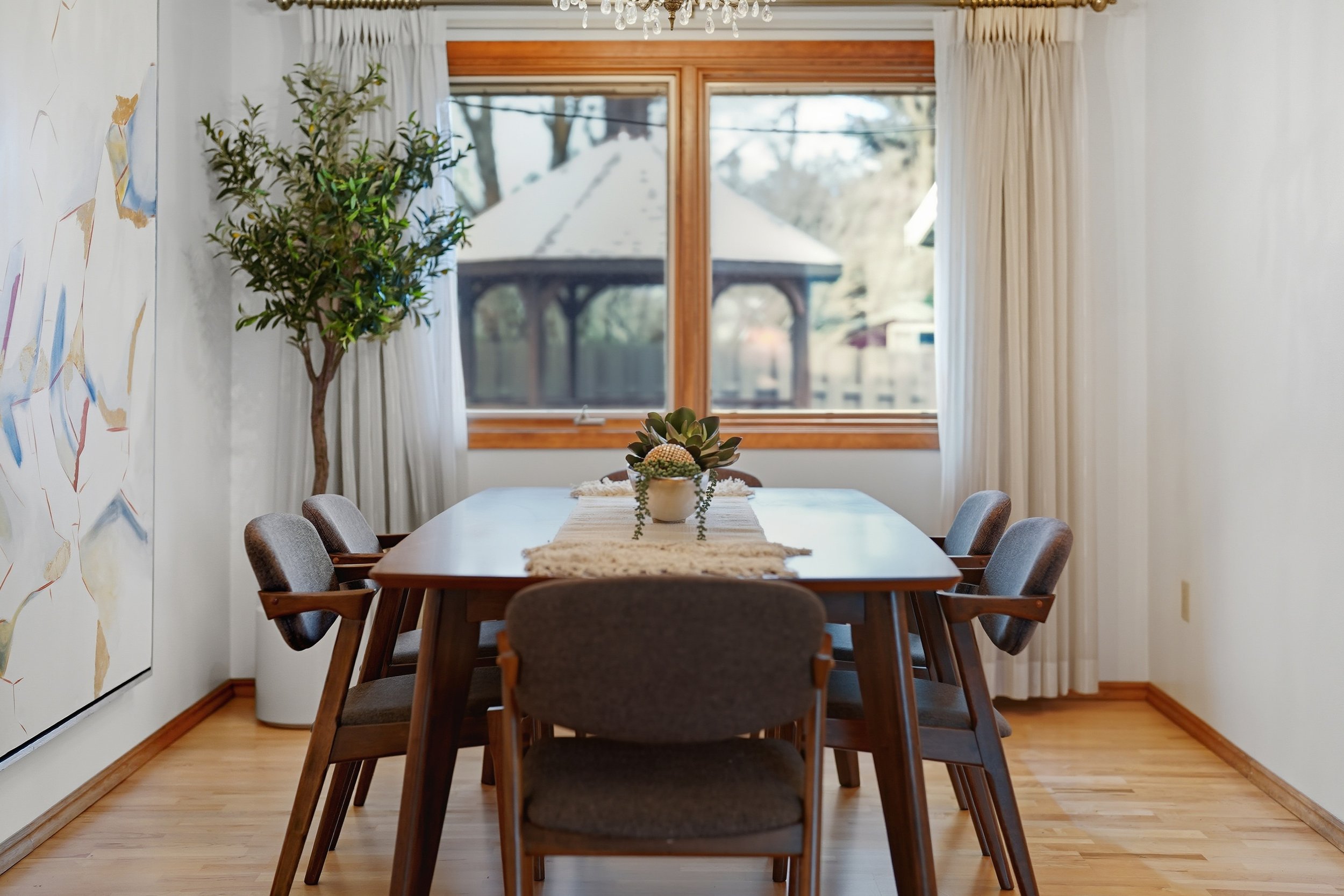 A wood-trimmed dining room with a round table and leather seating. Staging by Home Staging Works.