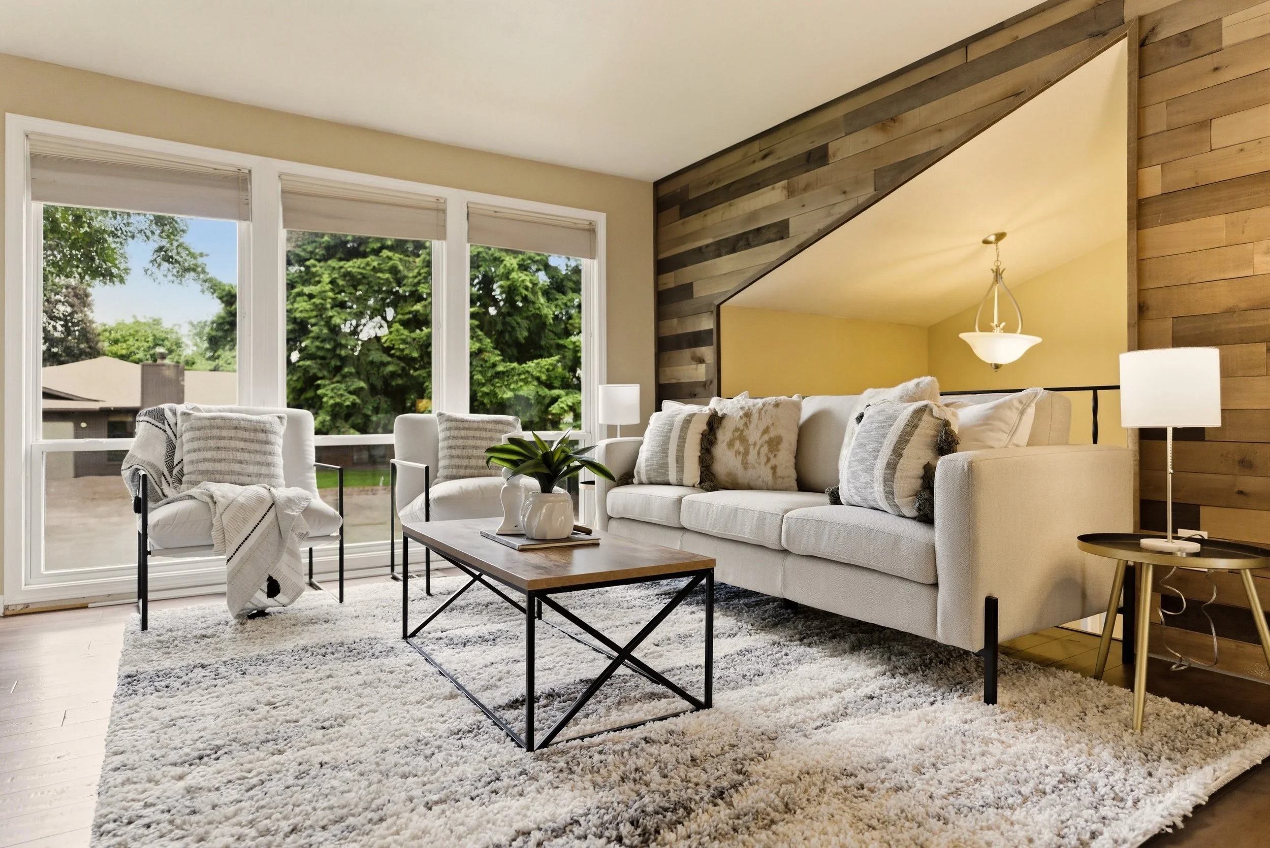 A warm, architectural living space with a cream sectional and natural greenery. Staging by Home Staging Works.