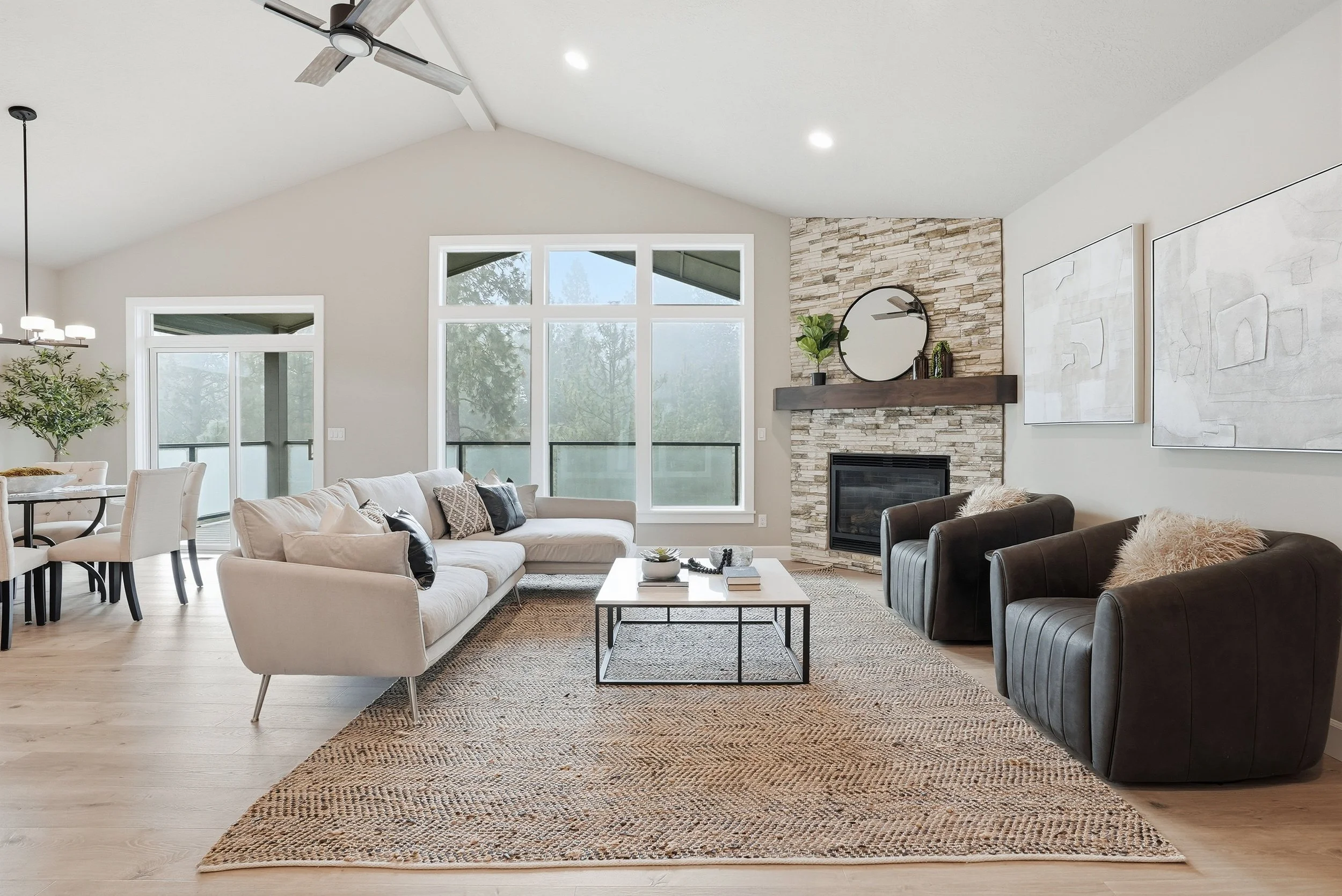 A bright living room arranged around a stone fireplace with relaxed neutral seating. Staging by Home Staging Works.