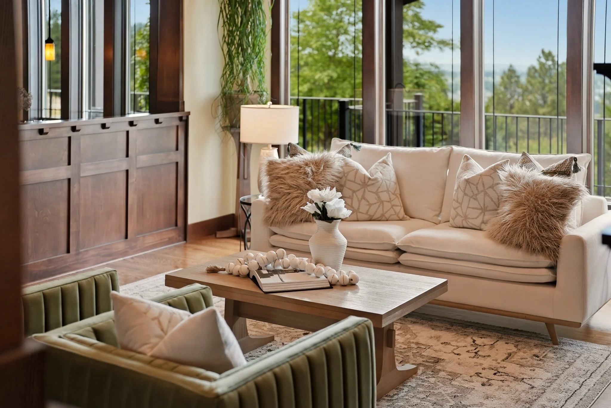 Cream sofa and olive-green accent chair beside tall windows and warm wood details in an HSW-staged home.