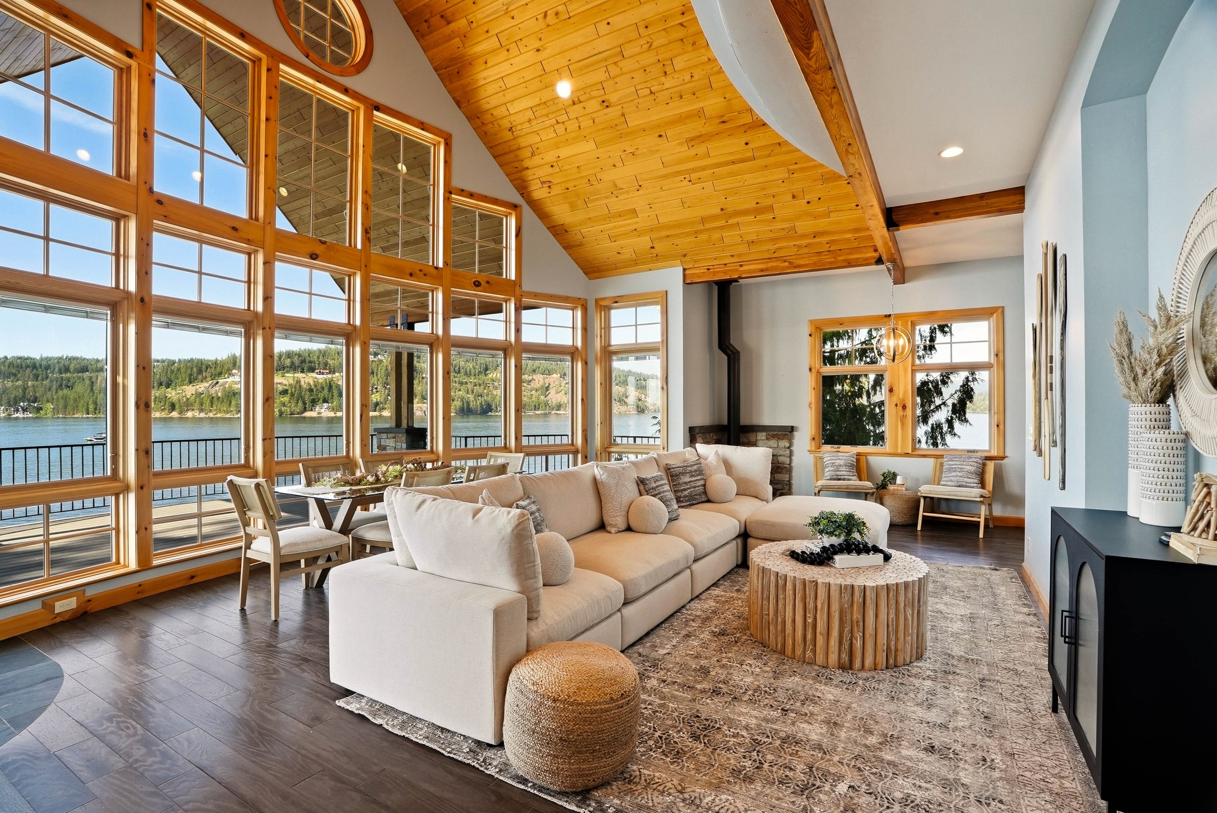 A vaulted living room with warm wood ceilings, a white sectional and expansive views. Staging by Home Staging Works.