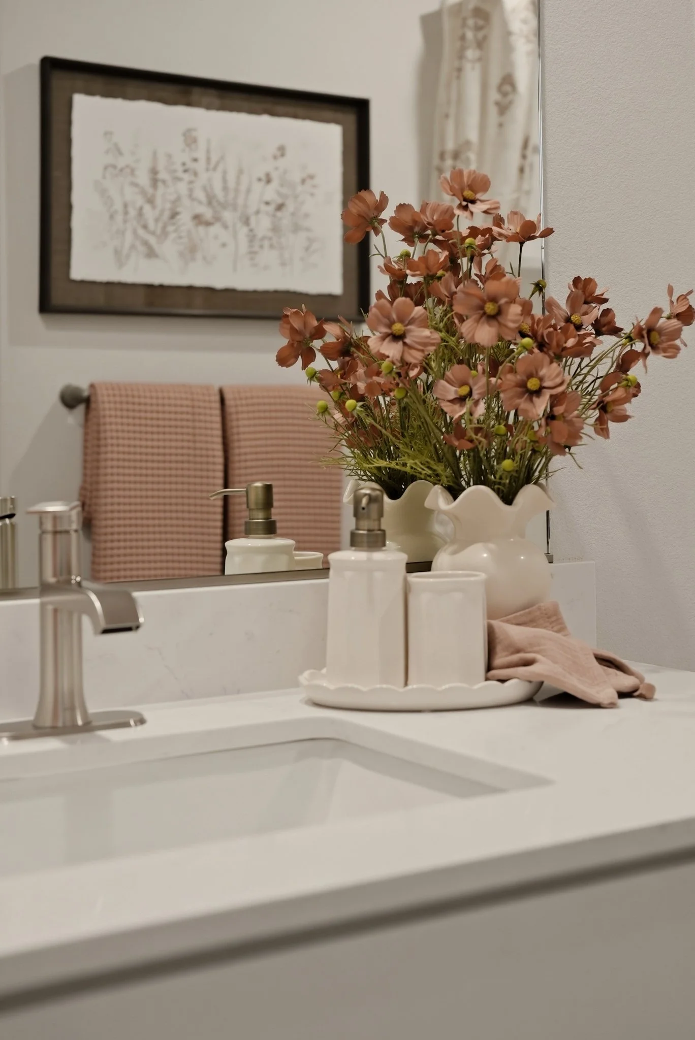 Fresh pink flowers and considered accessories bring warmth to a kitchen island. Styling by Home Staging Works.