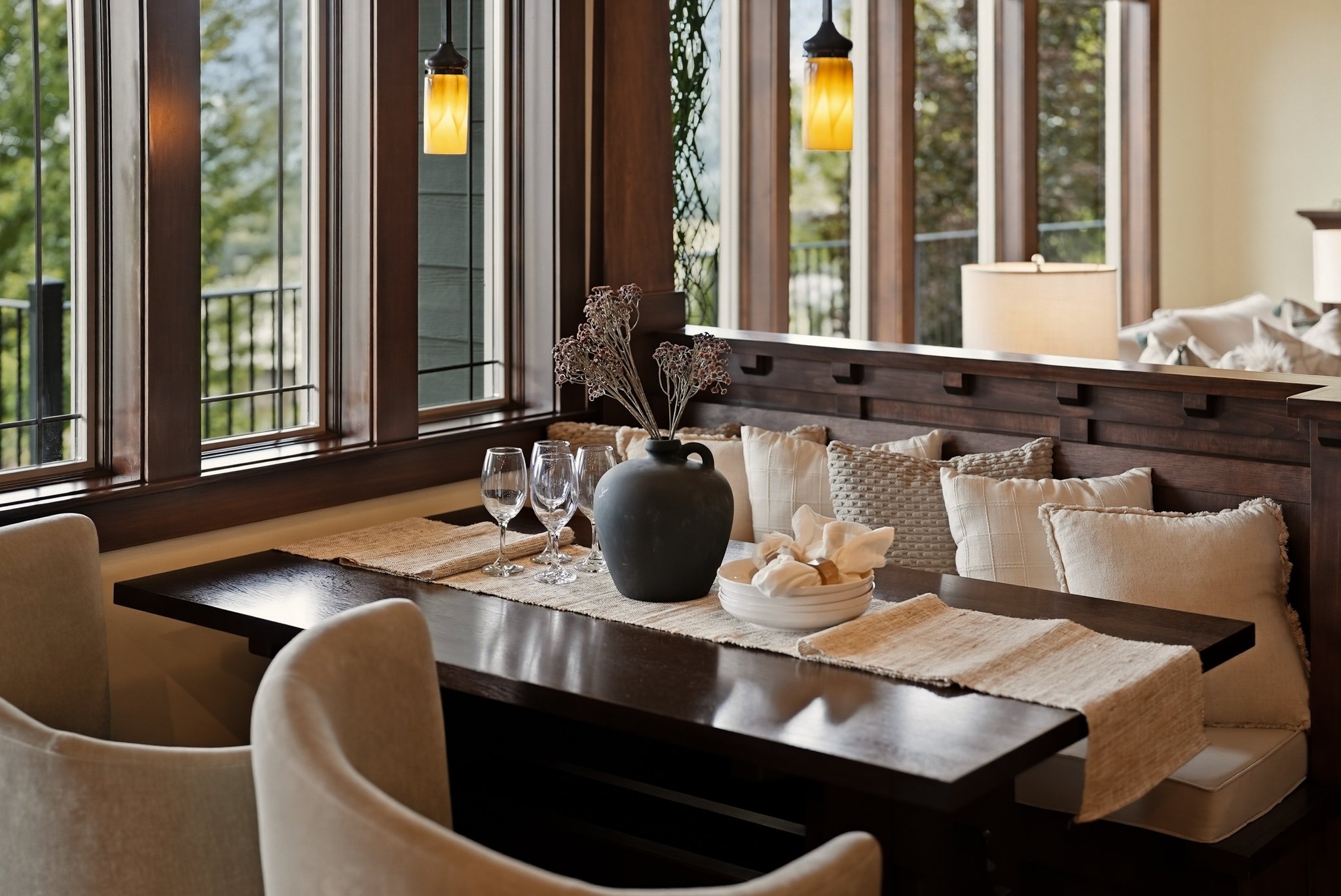 A warm dining room with wood paneling, gold pendants and upholstered chairs. Staging by Home Staging Works.