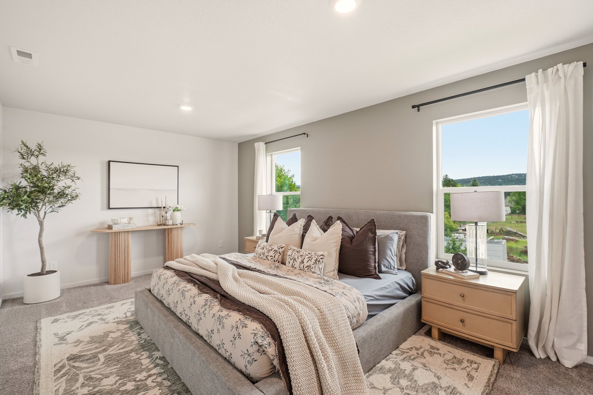 Primary bedroom staged by HSW with layered neutral bedding, matching wood nightstands and soft natural light.