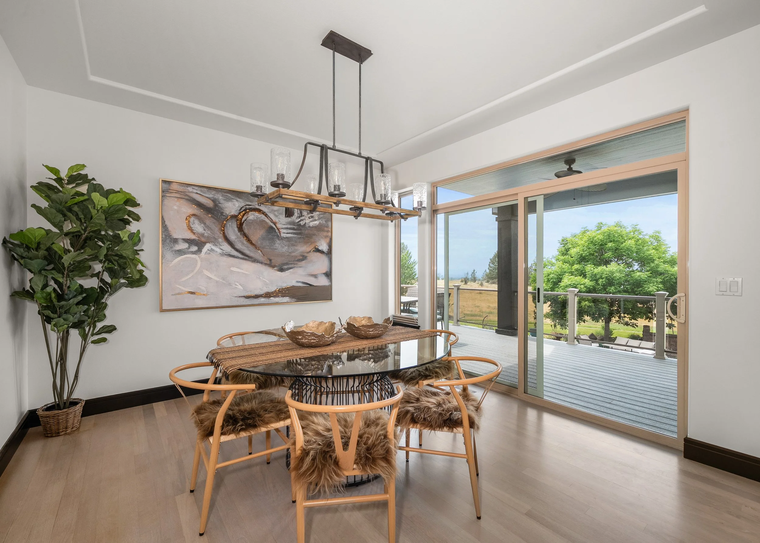 HSW-staged dining room with a round table, sculptural wood chairs, artwork and greenery.