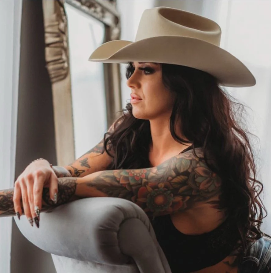 Ashli in a cowboy hat, seated by a window