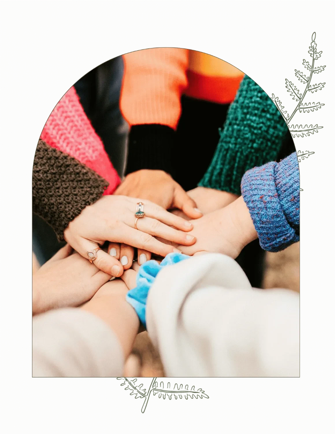 Multiple hands joined together in a circle, symbolizing unity and teamwork, with individuals wearing colorful sweaters and rings.