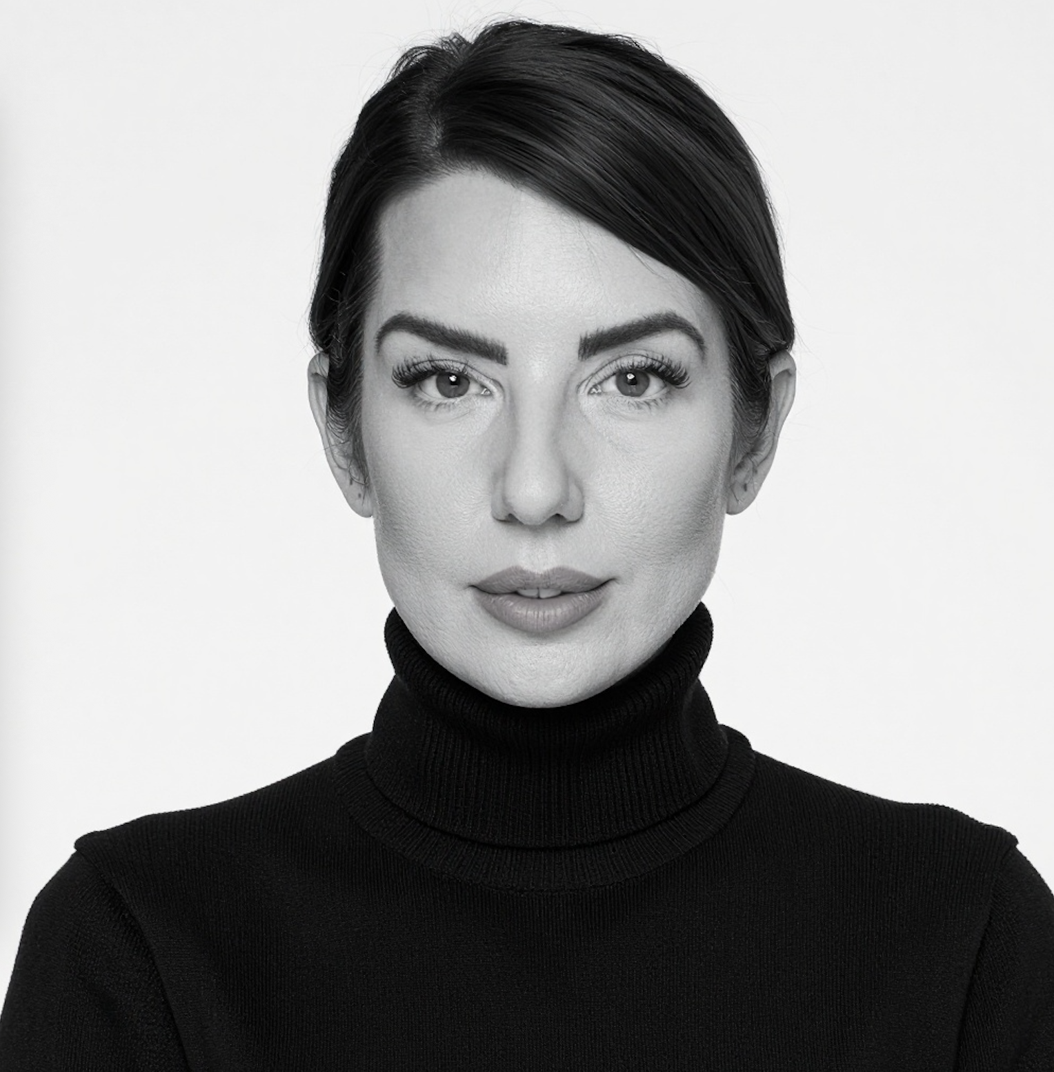 Black and white portrait of a woman with dark hair in a bun, wearing a black turtleneck sweater, looking directly at the camera with a neutral expression.