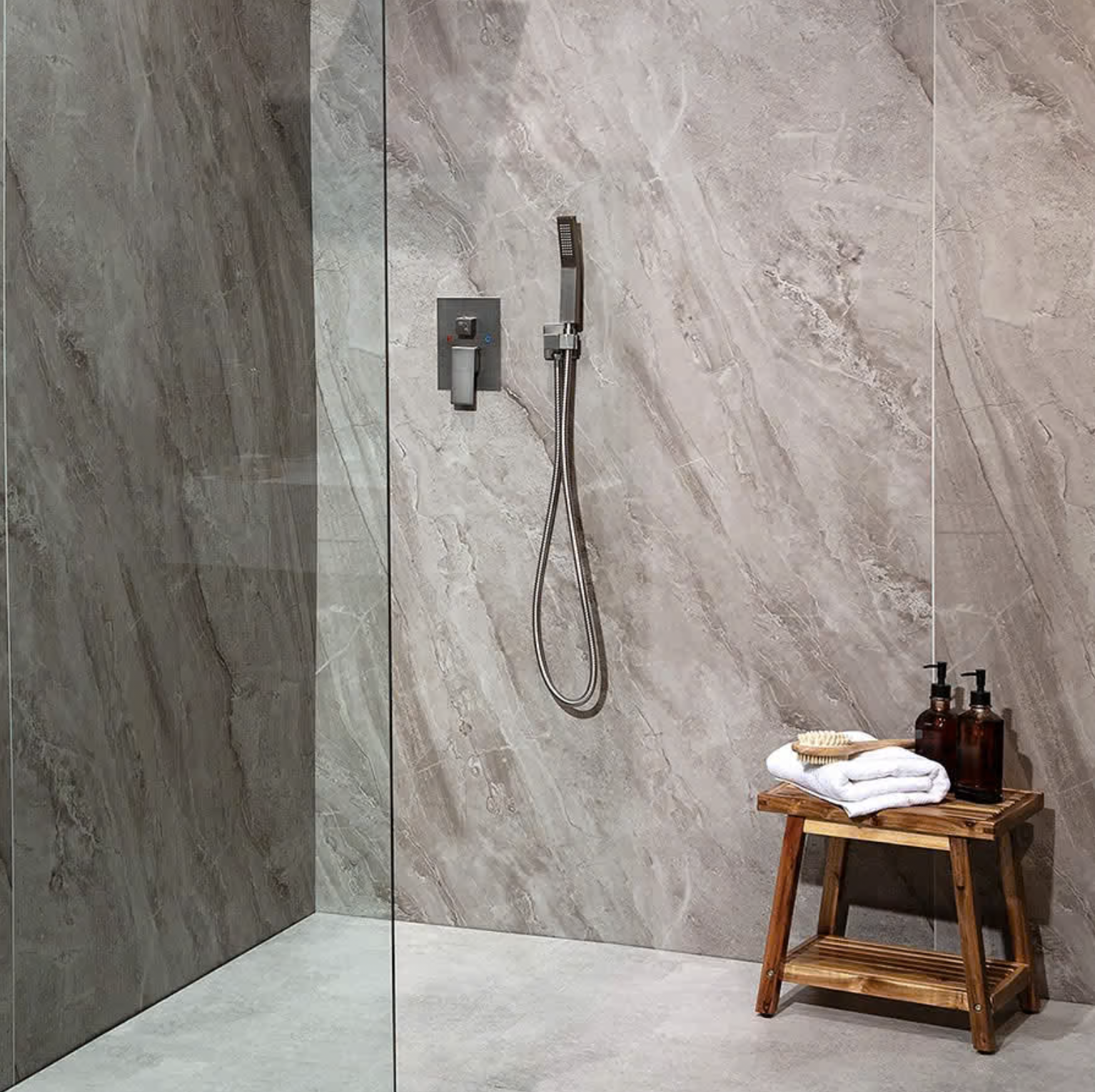 Gray stone walls, handheld shower, wood stool:
Grout-free gray stone-look shower wall panels with a handheld shower head and frameless glass panel
