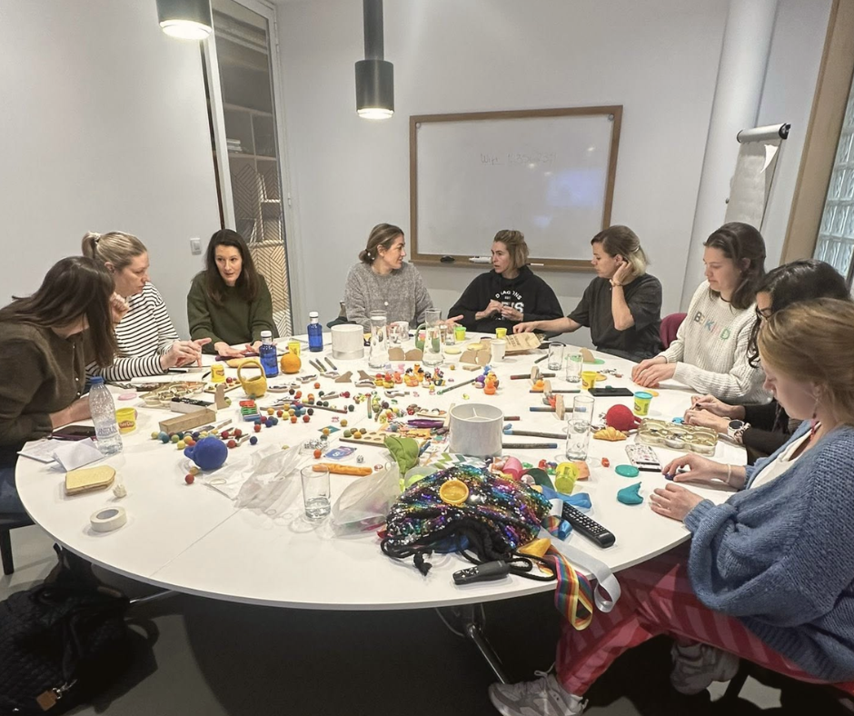 Teachers discussing play materials around a table at Getting Ready to Write training in Madrid.
