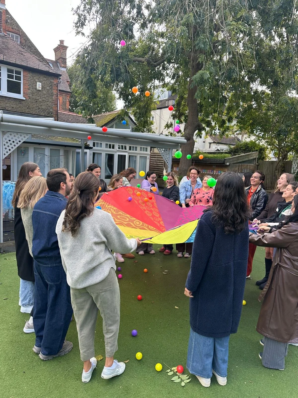 The Gwendolen House nursery team playing with a colourful parachute during behaviour training in London.