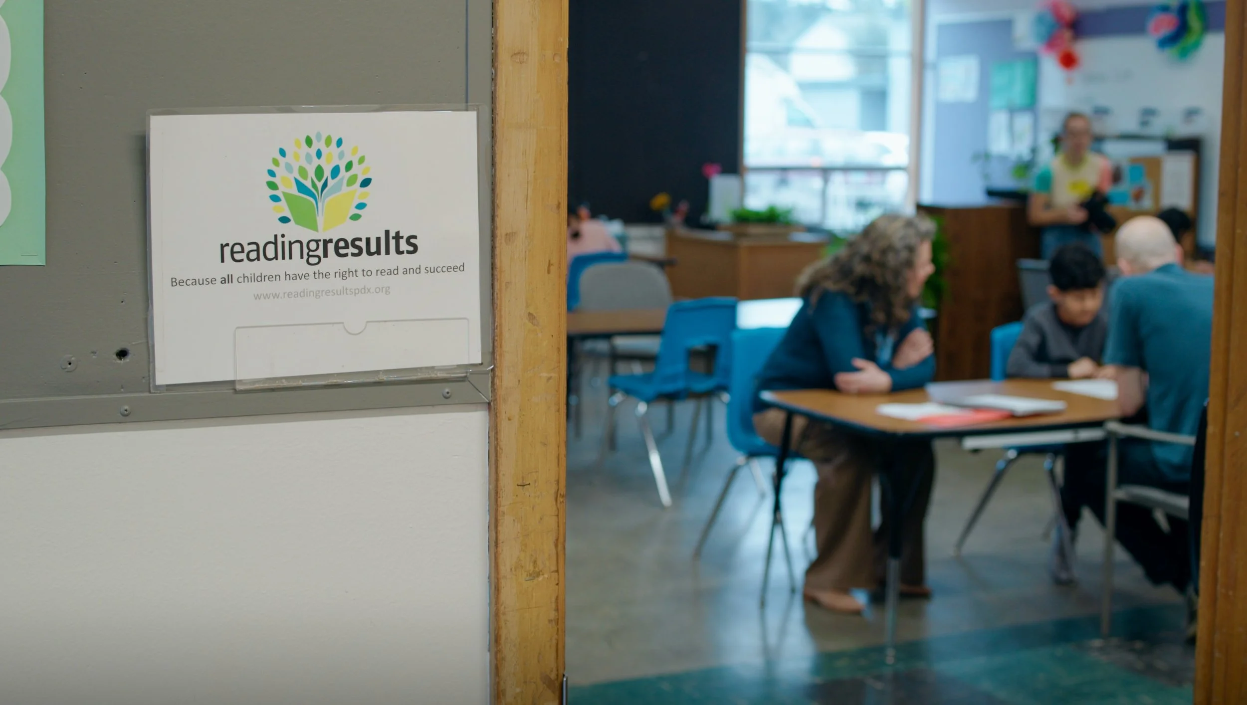 Reading Results sign outside a classroom with students seated at tables inside